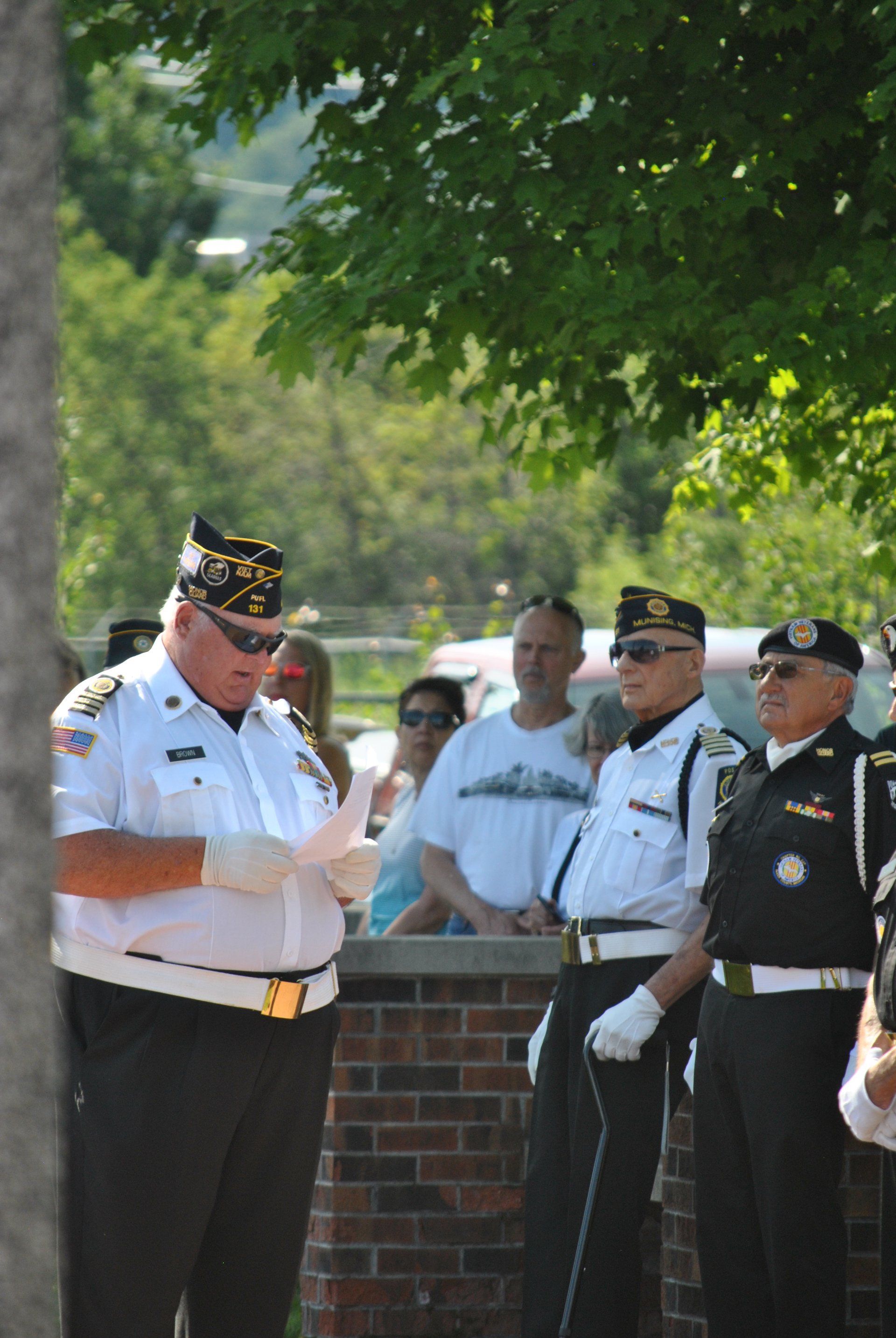 A man in a white uniform is standing in front of a group of men in uniform.