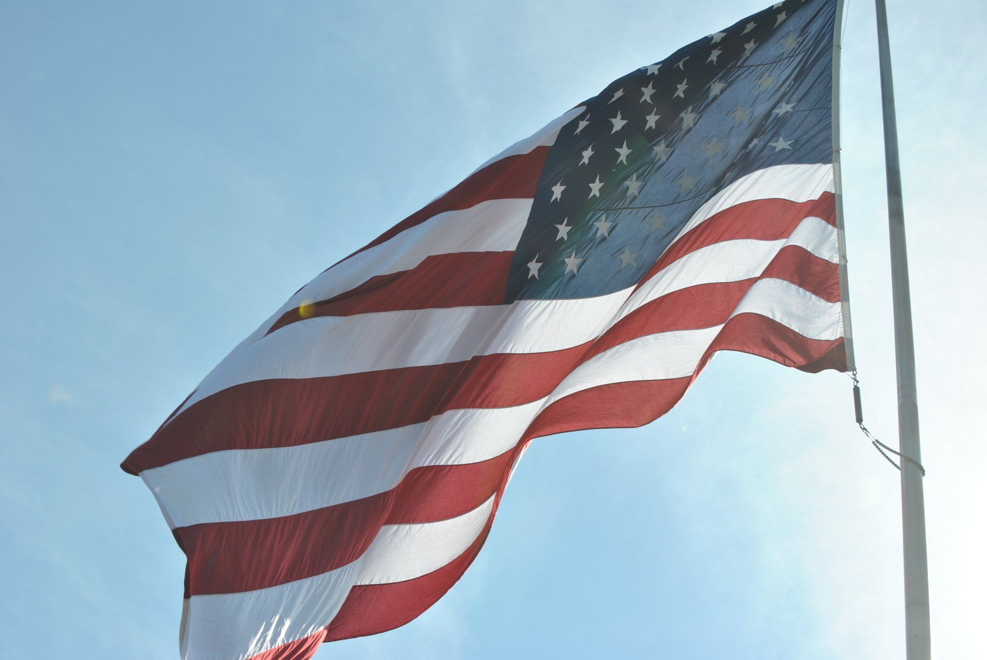 An american flag is waving in the wind against a blue sky