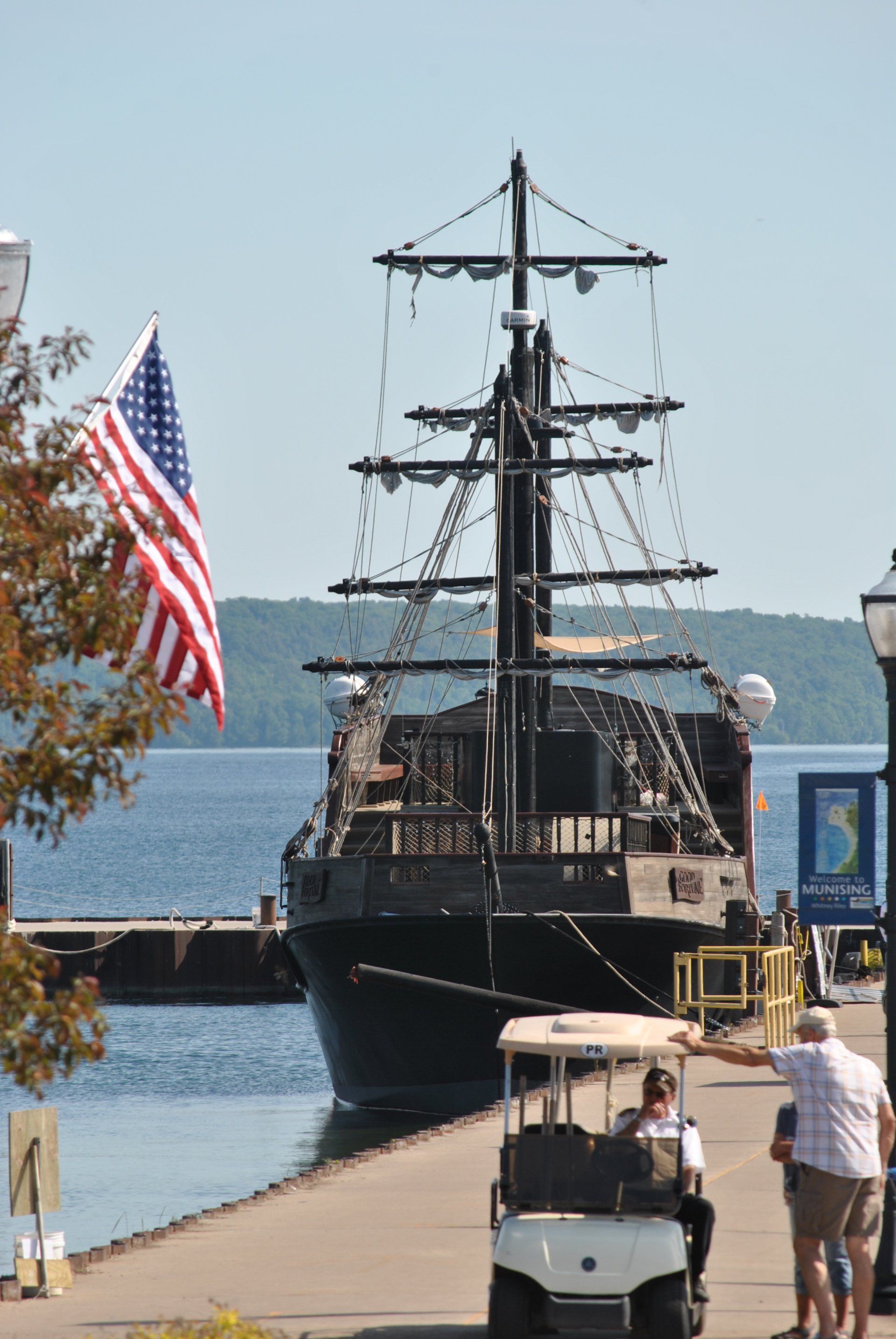 A pirate ship is docked at a dock next to a golf cart