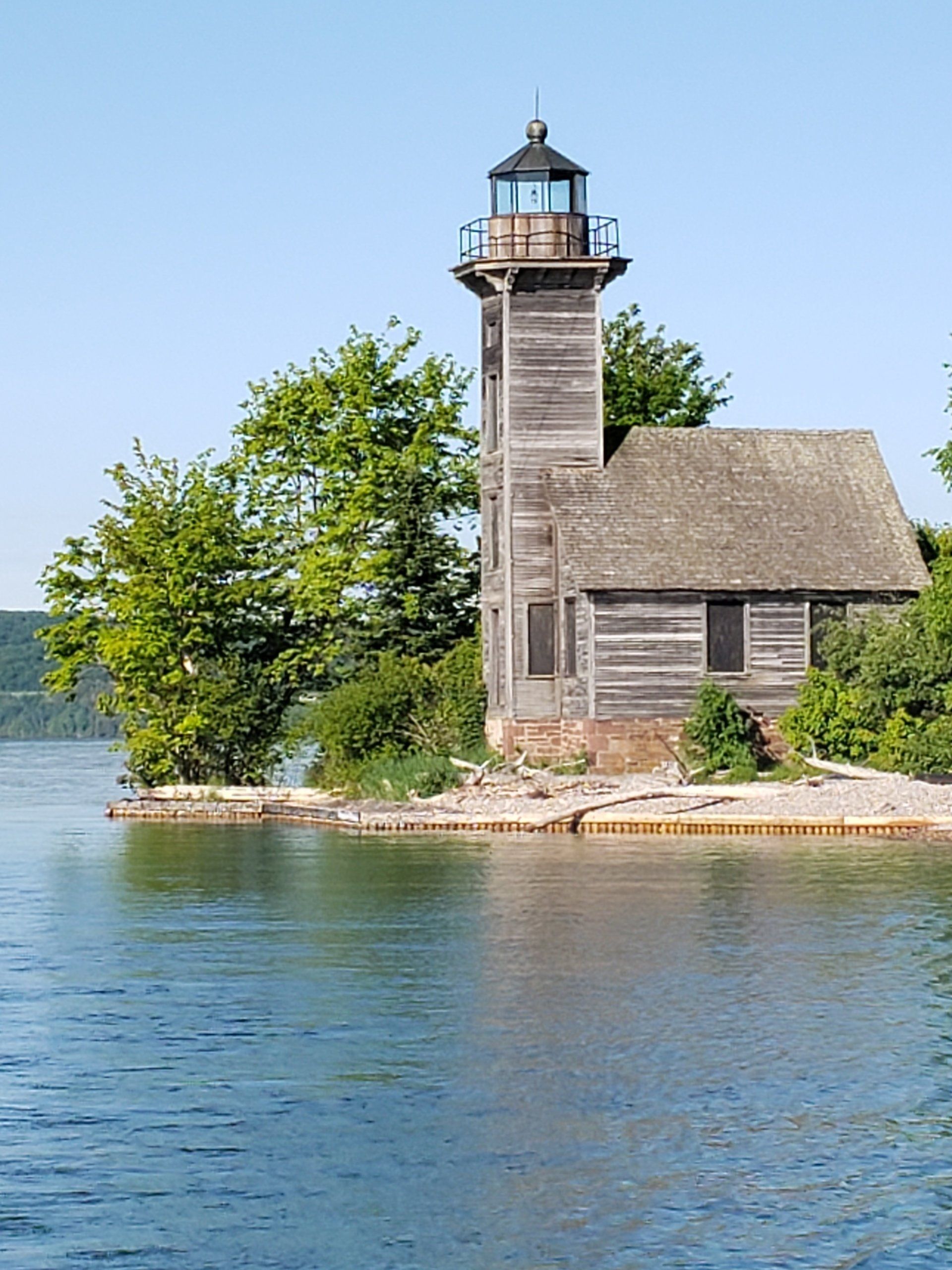 A lighthouse sits on a small island in the middle of a lake