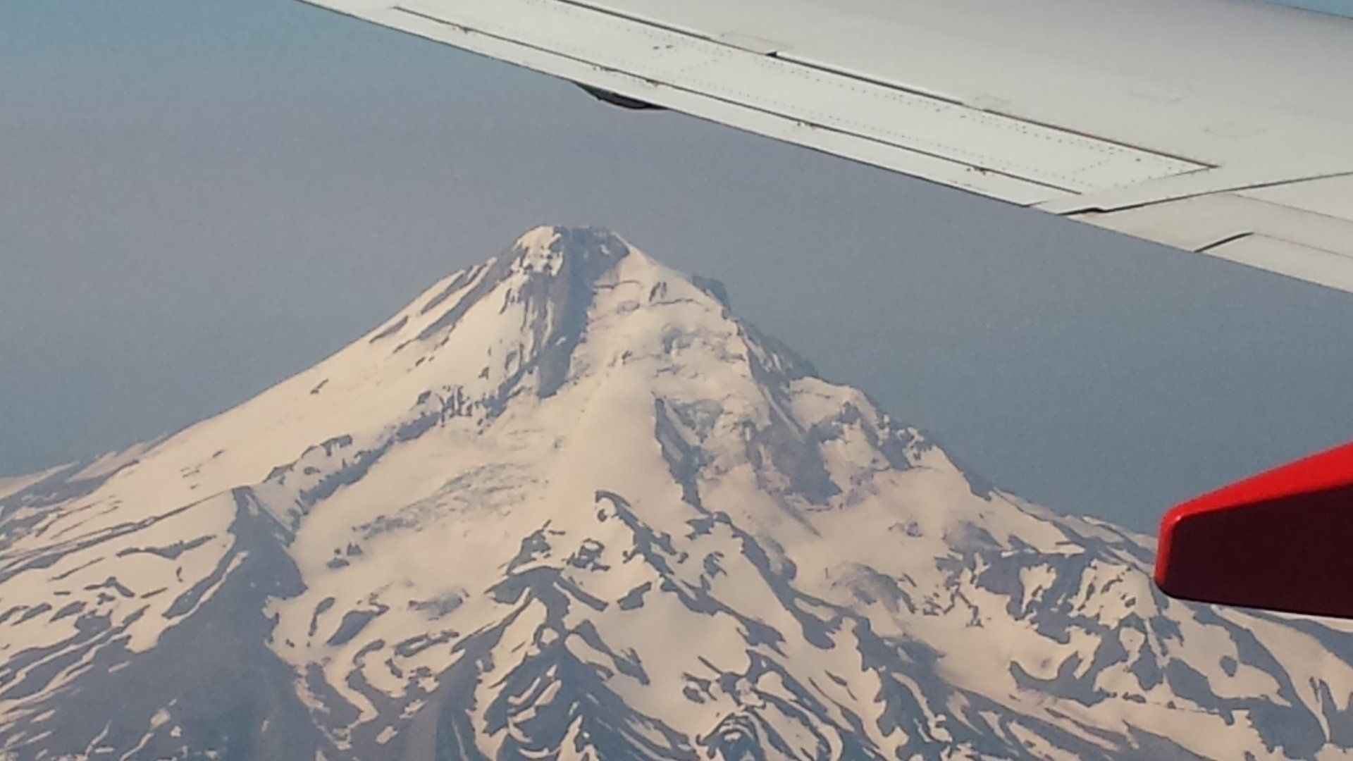 A plane is flying over a snowy mountain range