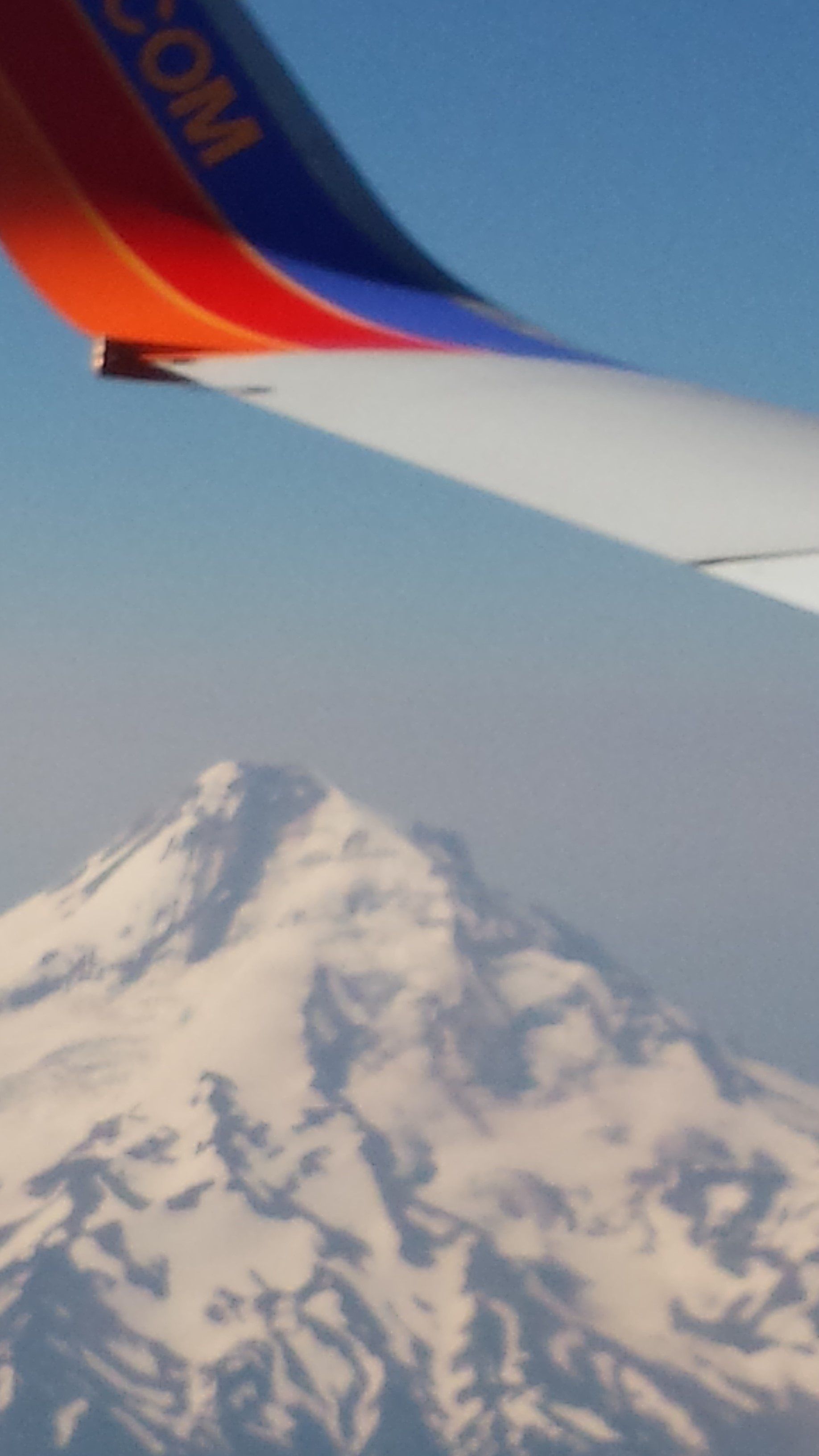A southwest airlines plane is flying over a snowy mountain