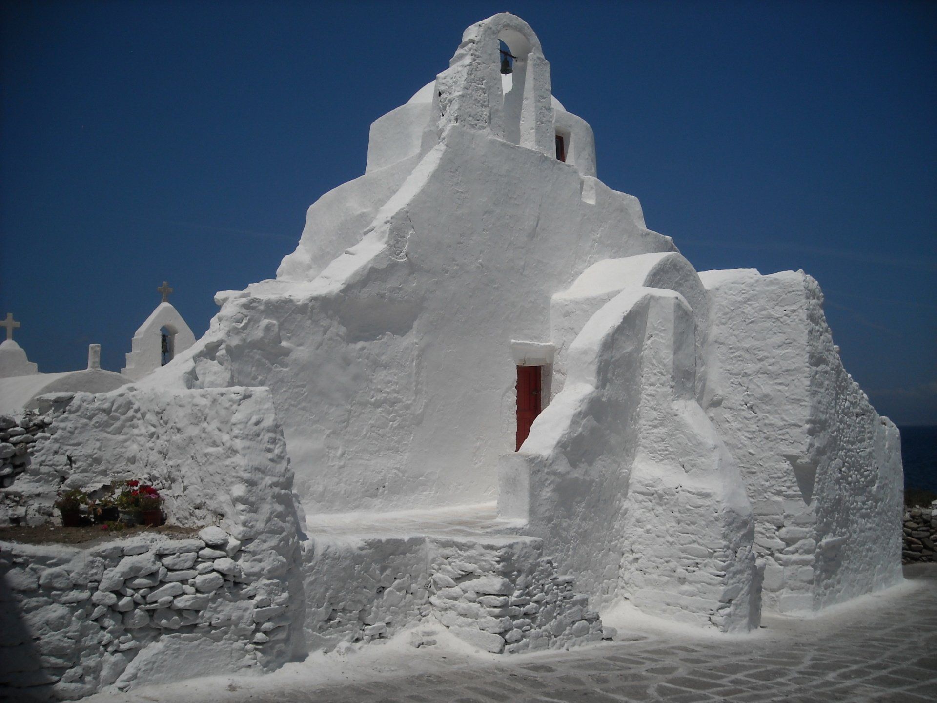 A white building with a red door and a blue sky in the background