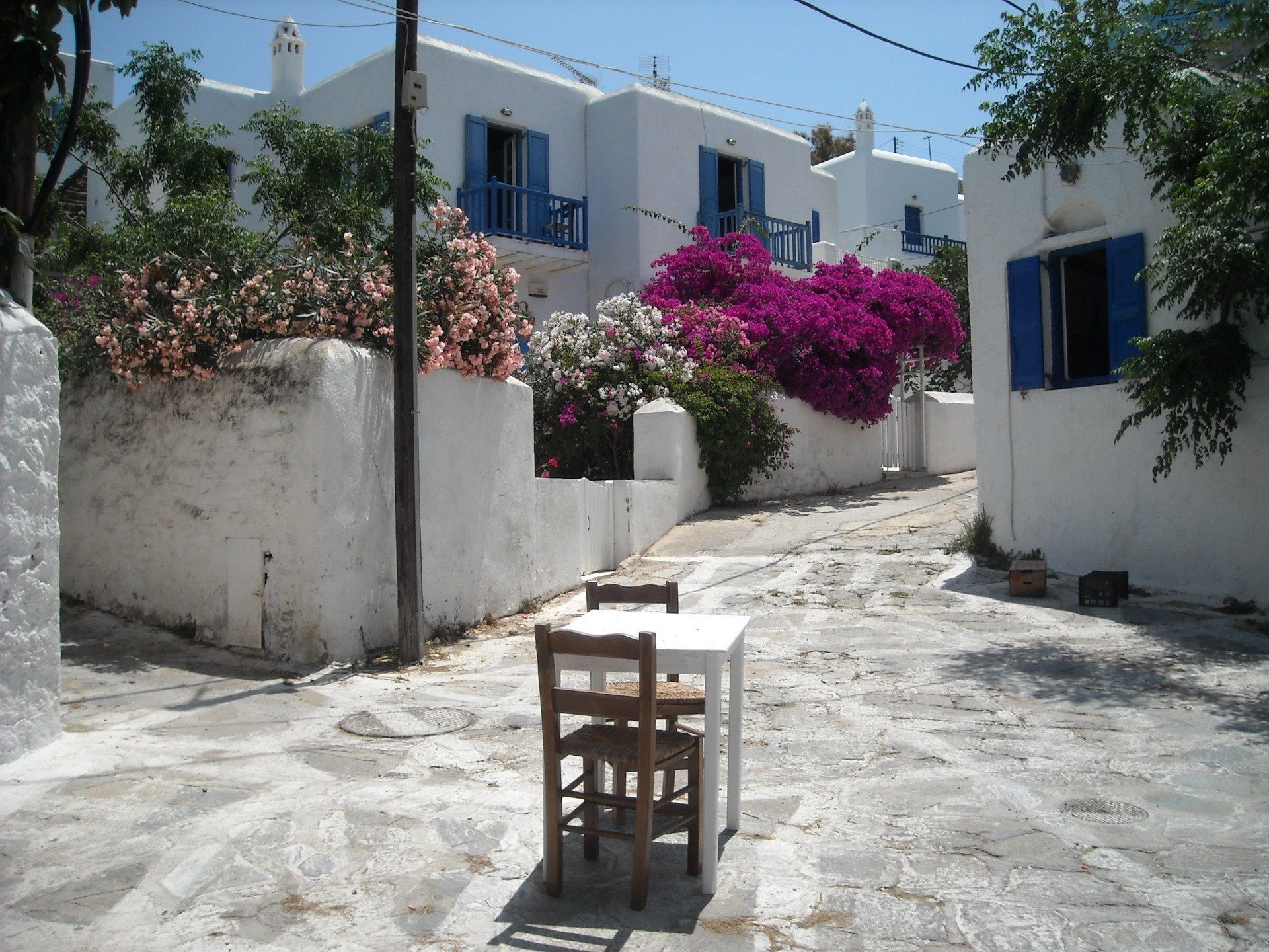 A white table and chairs in a narrow alleyway