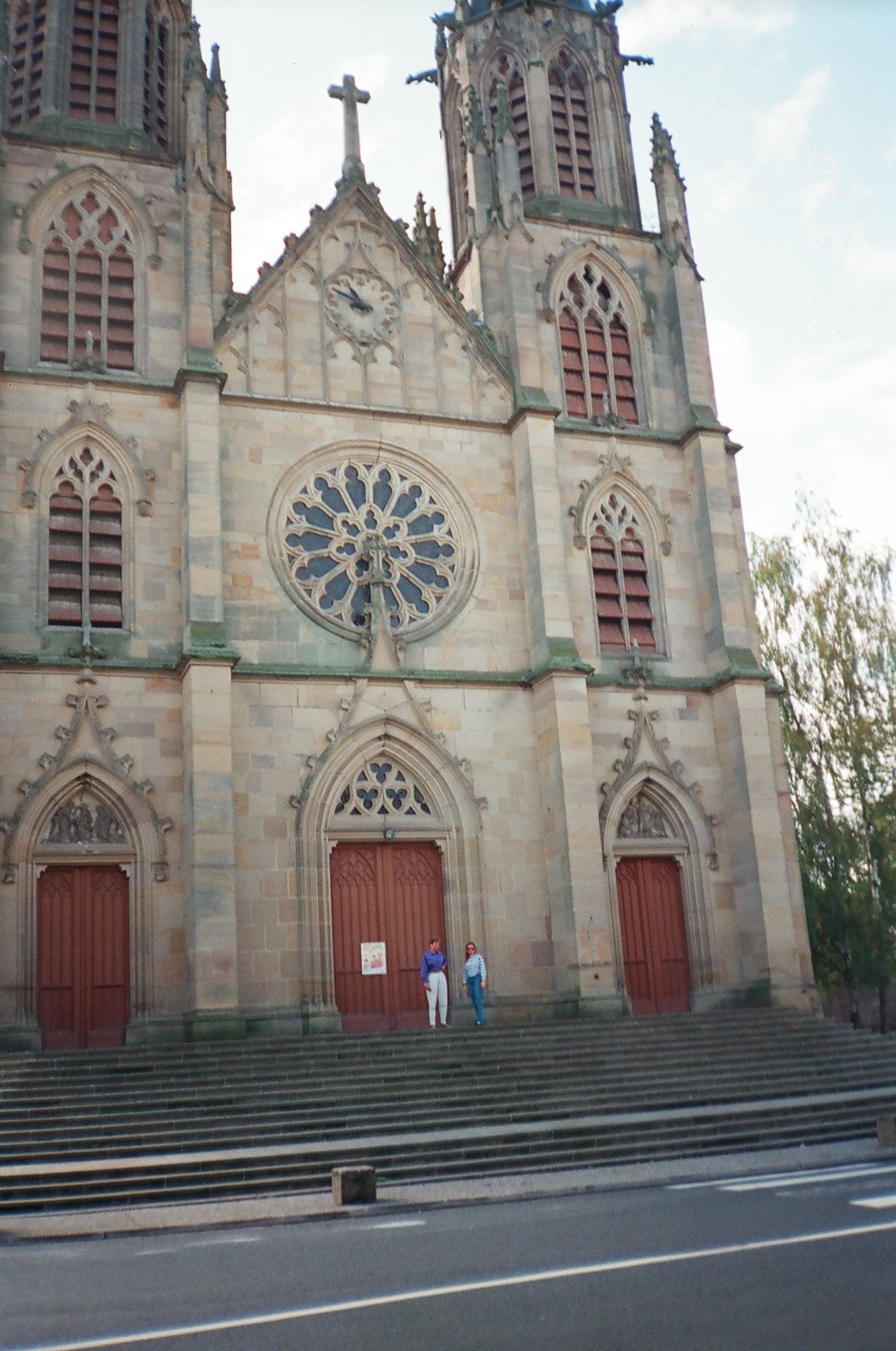 Two people are standing on the steps of a large church