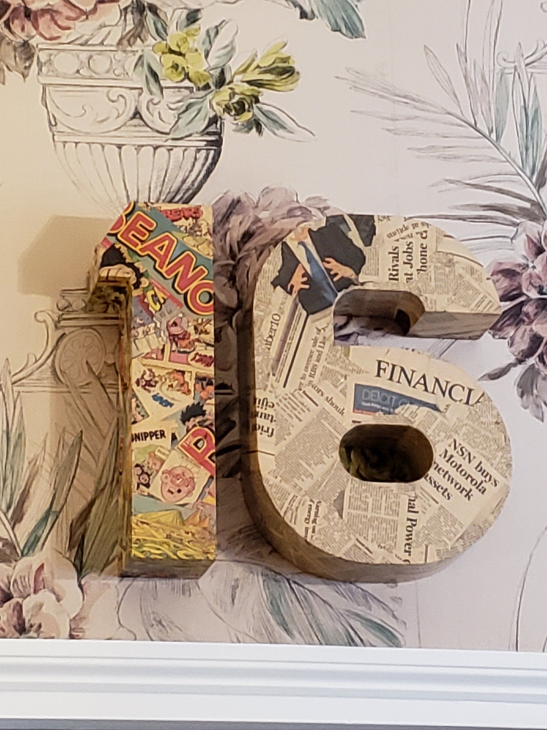 The letter s is made out of newspaper and has the word finance on it