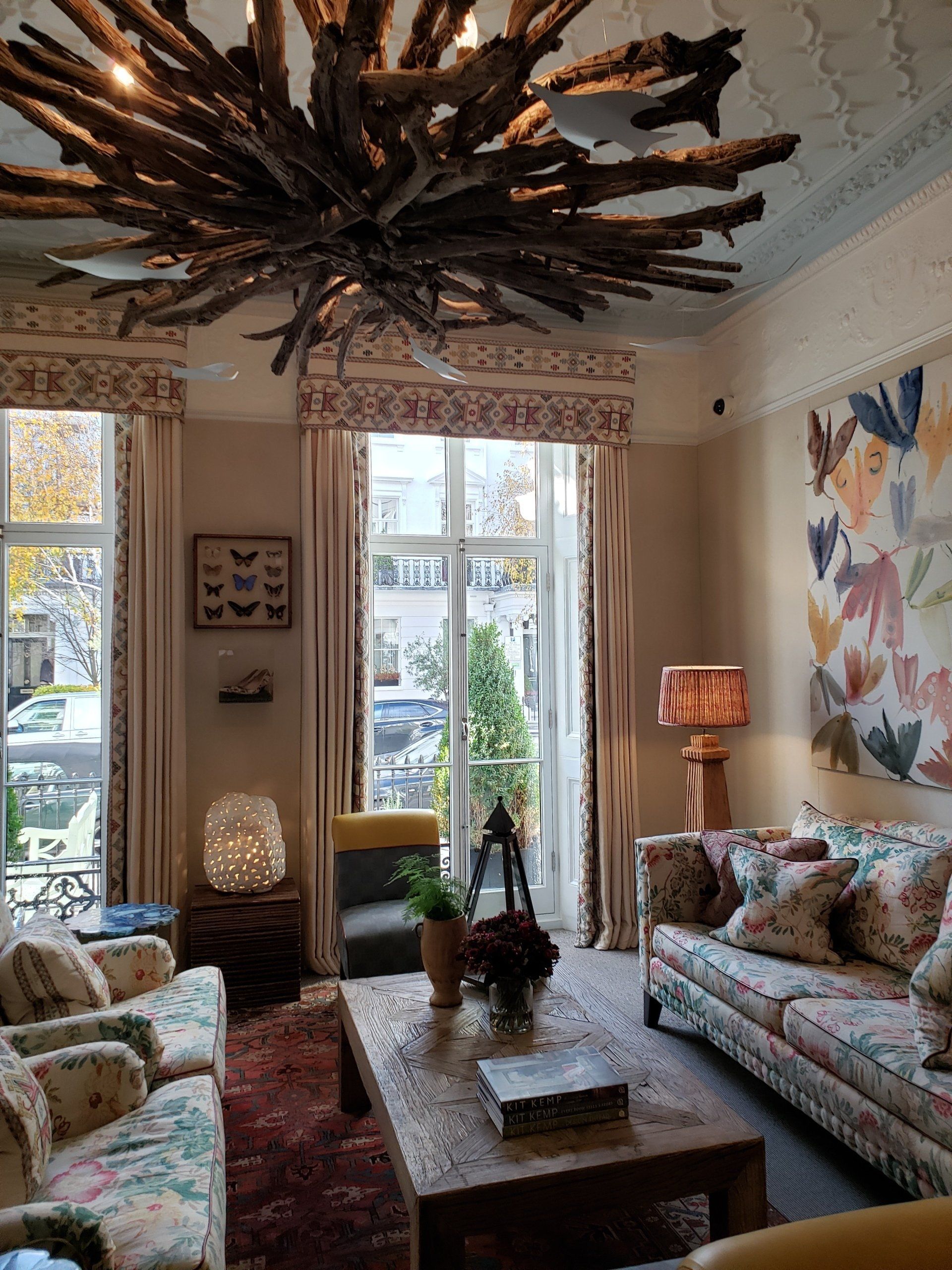 A living room with a couch , chairs , table , and chandelier.