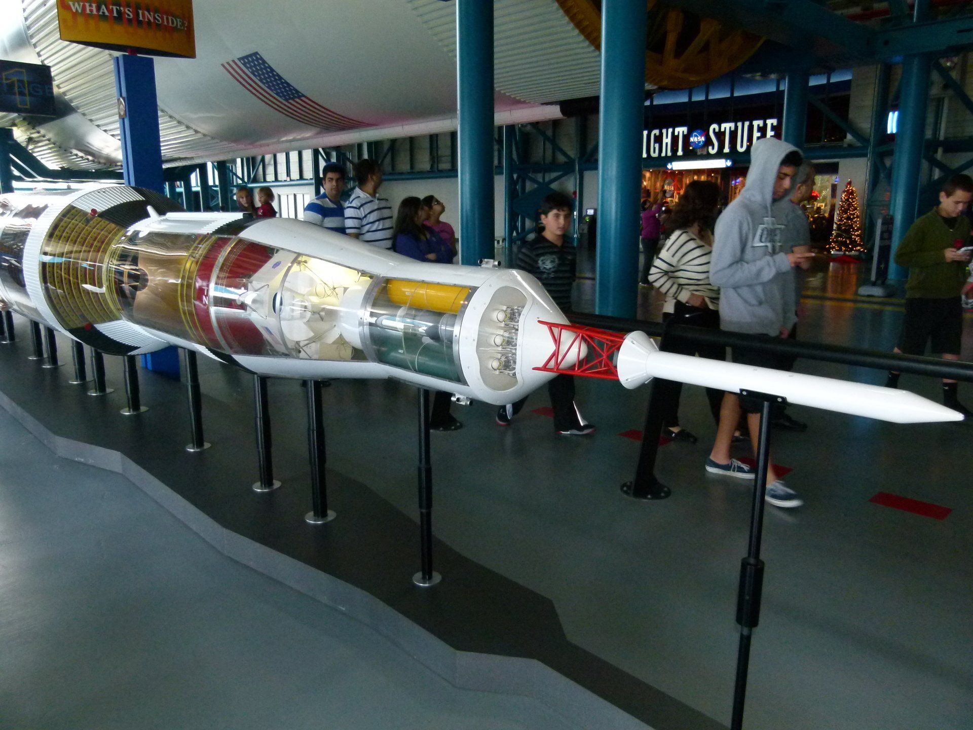 People looking at a model of a rocket in front of a sign that says ight stuff