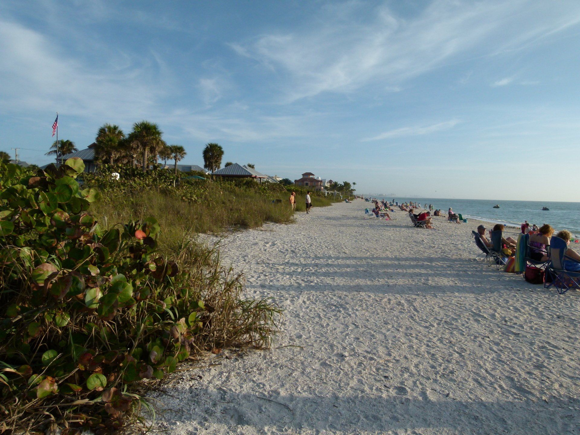 A group of people are sitting on the beach near the ocean