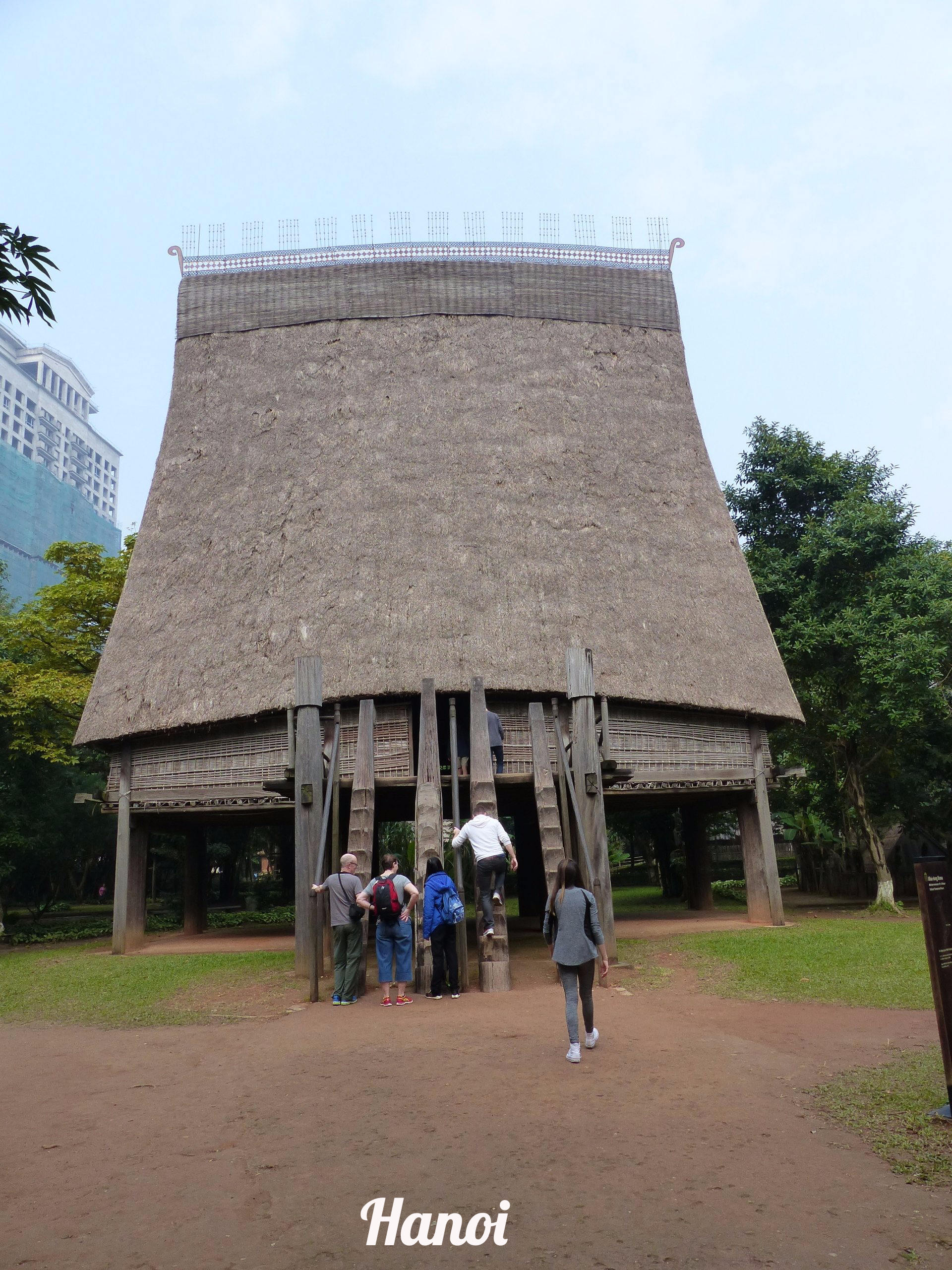 A group of people standing in front of a thatched hut in hanoi