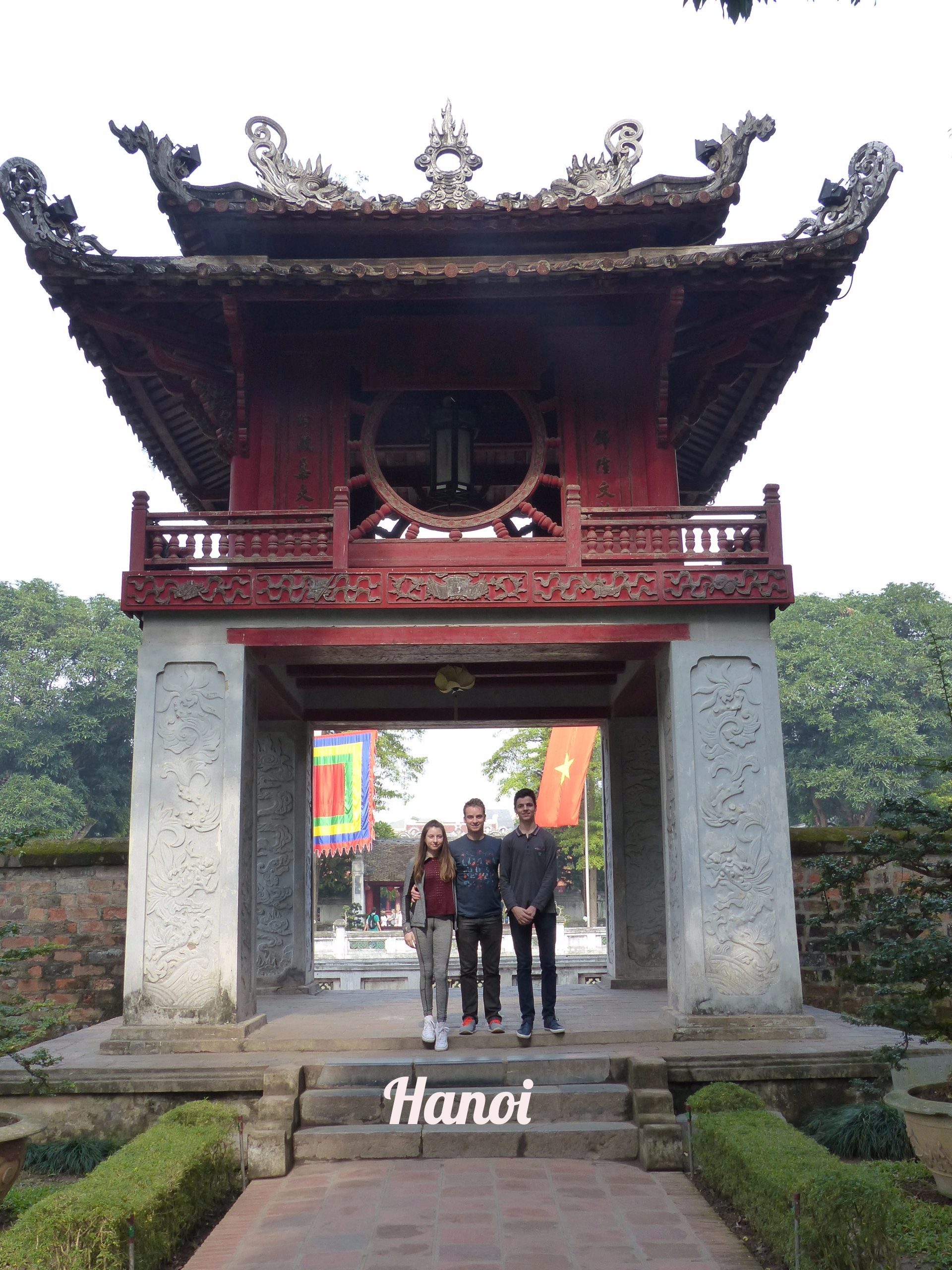 A group of people standing in front of a building with hanoi written on the steps