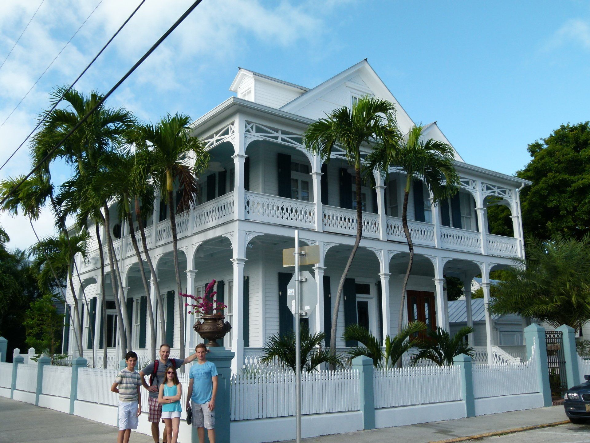 A group of people standing in front of a large white house