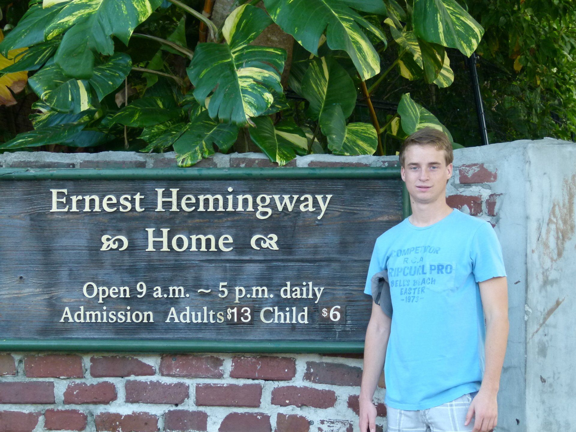 A young man stands in front of a sign for ernest hemingway 's home