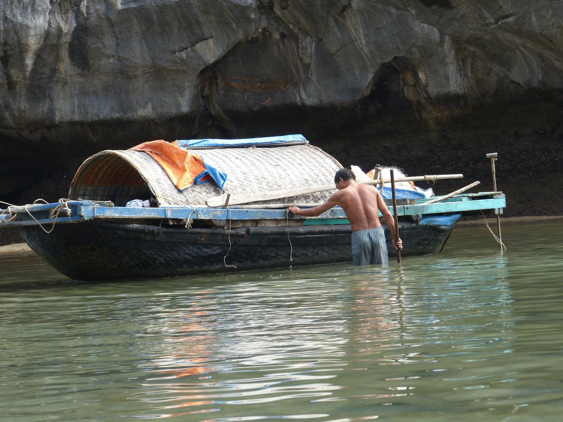 A man is standing in the water near a boat