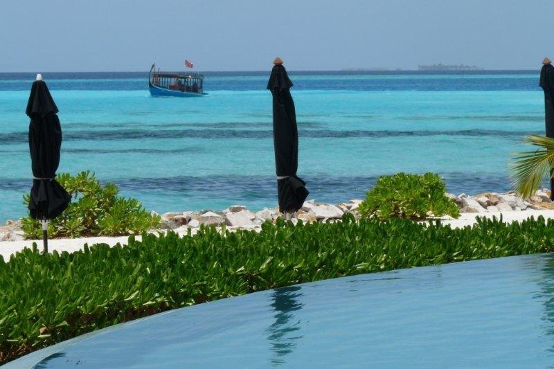 A swimming pool with umbrellas and a boat in the background