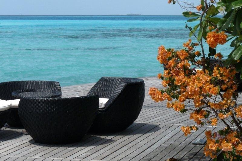 Two chairs and a table on a wooden deck overlooking the ocean