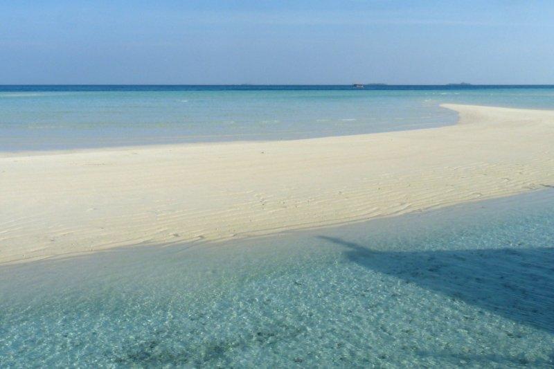 There is a sandy island in the middle of the ocean.