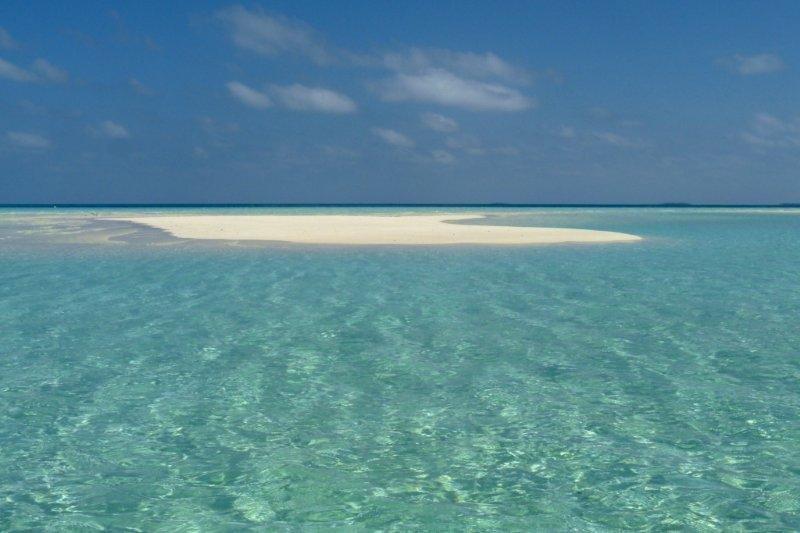 There is a small sandy island in the middle of the ocean.