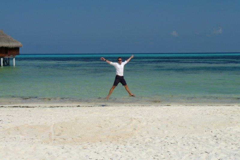 A man standing on a beach with his arms outstretched