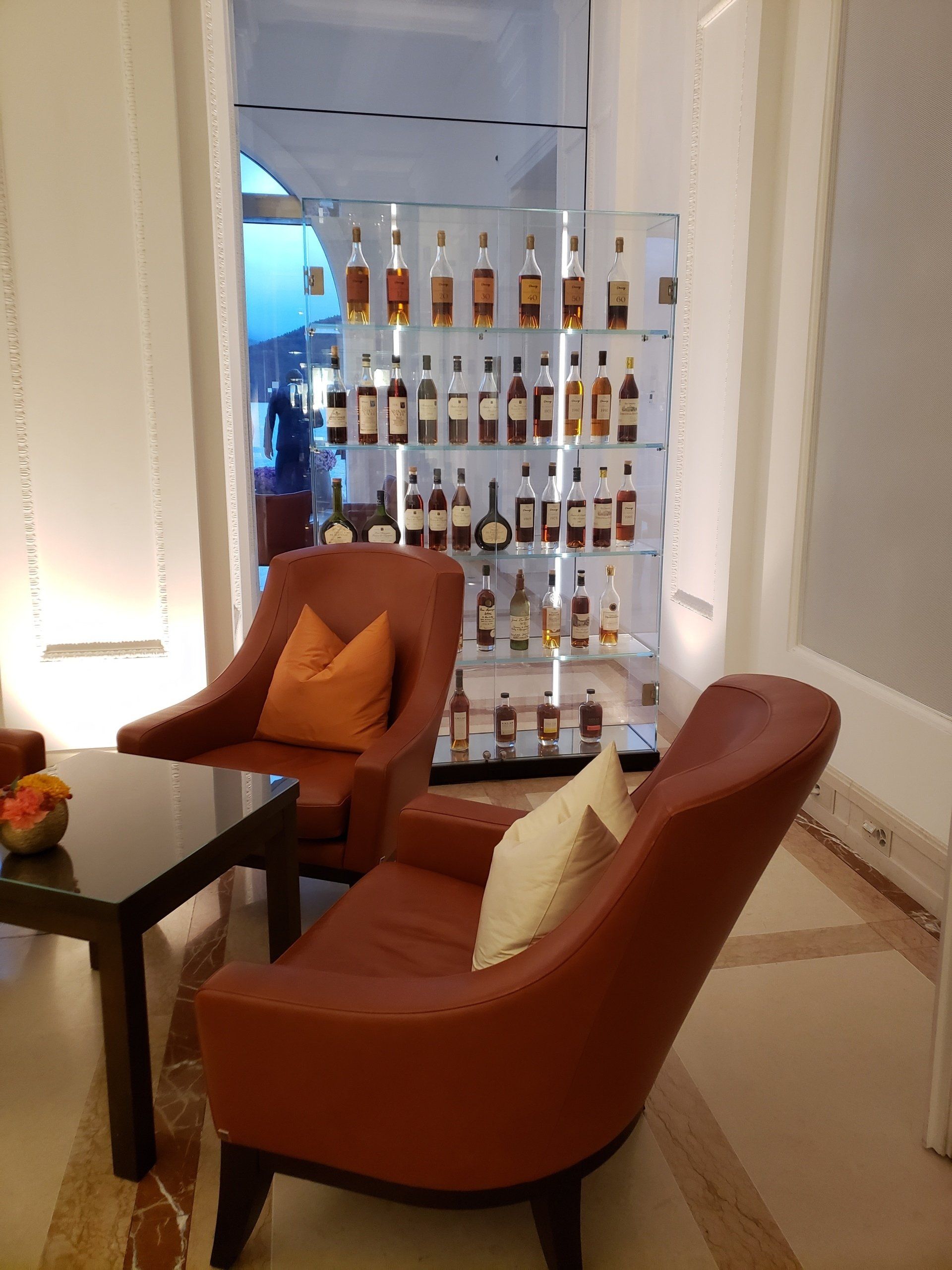 Two chairs and a table in front of a wall of bottles