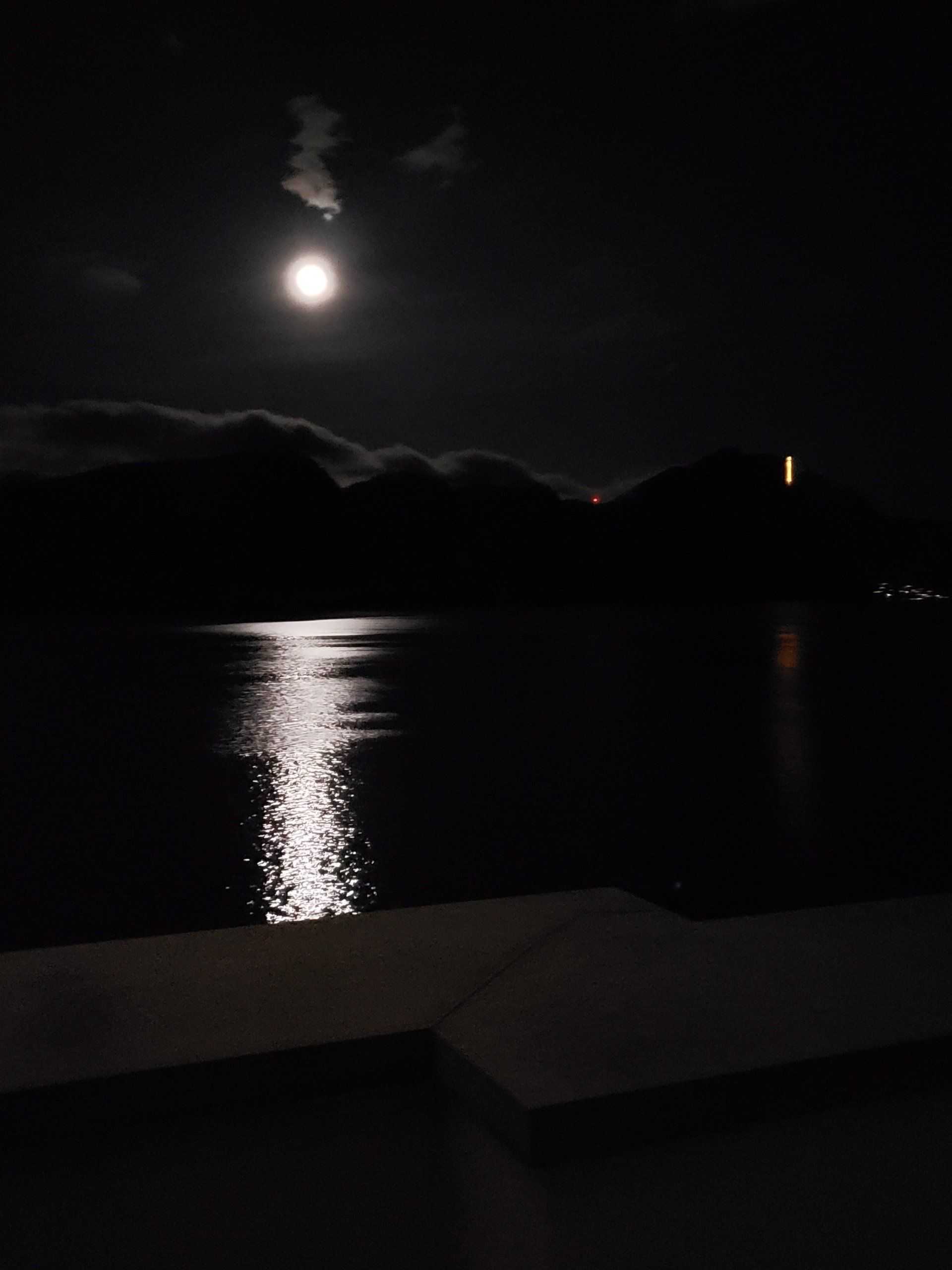A full moon shines over a body of water