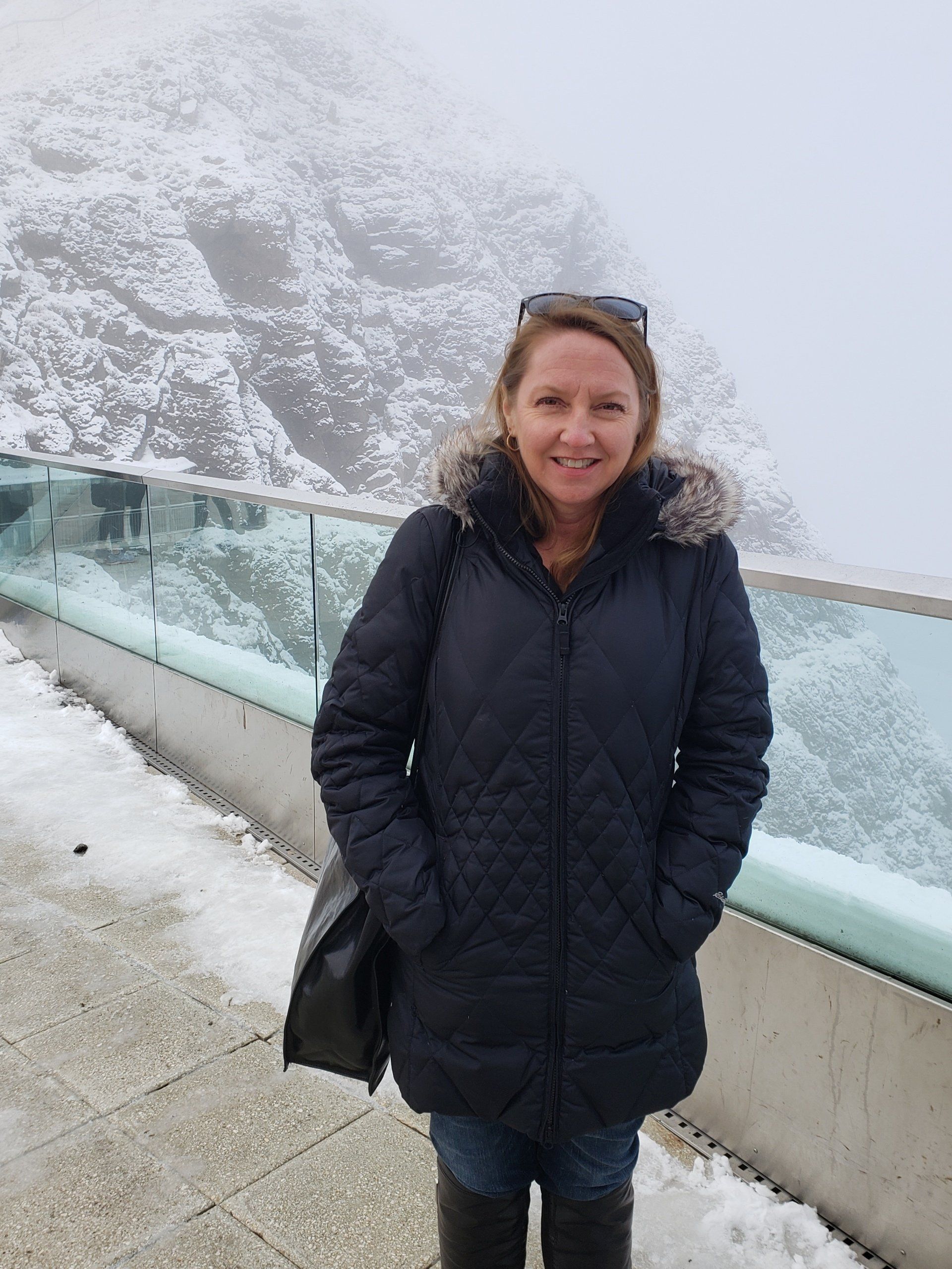 A woman in a black coat is standing in the snow.