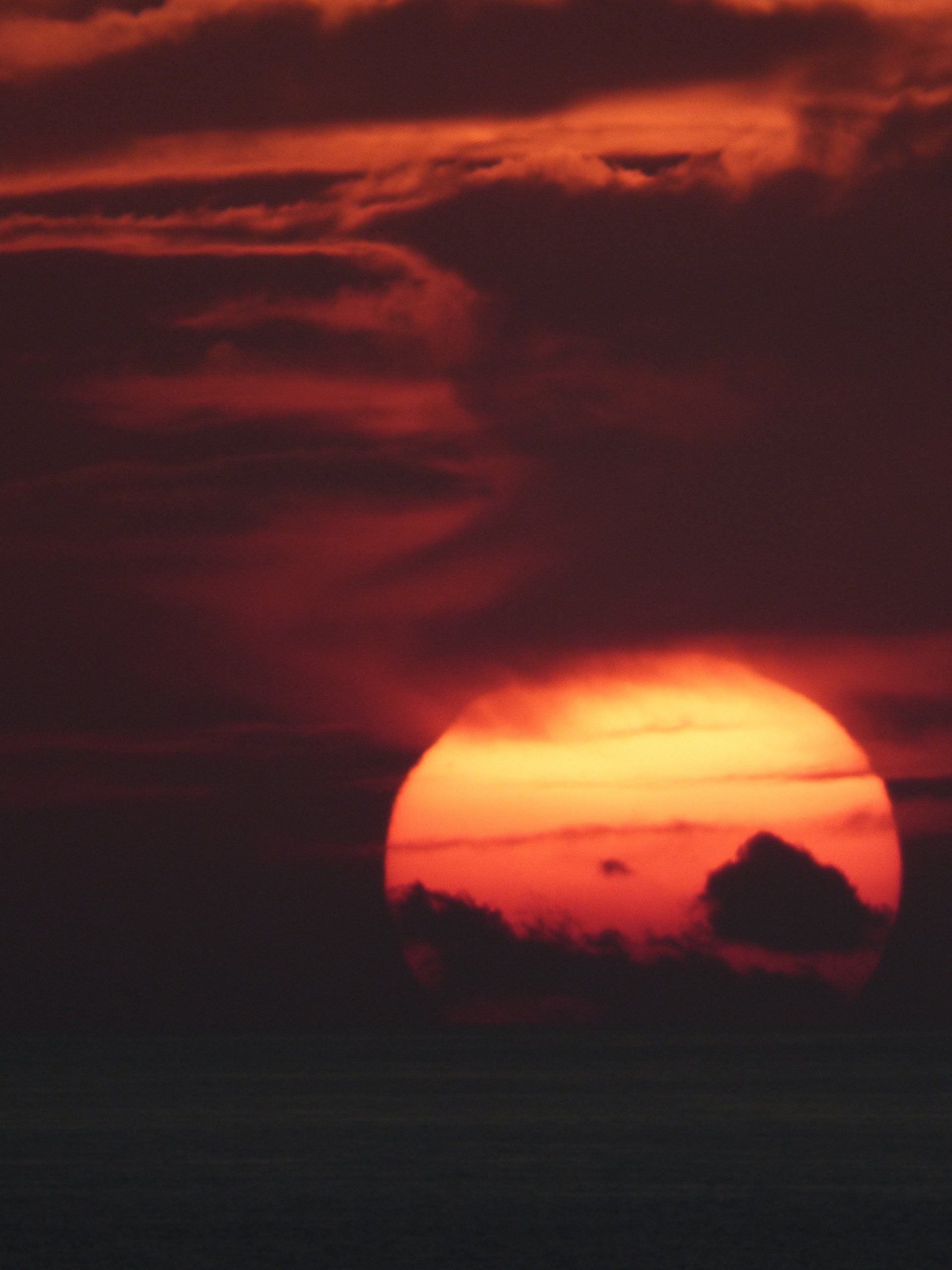 A close up of a sunset with the sun shining through the clouds.