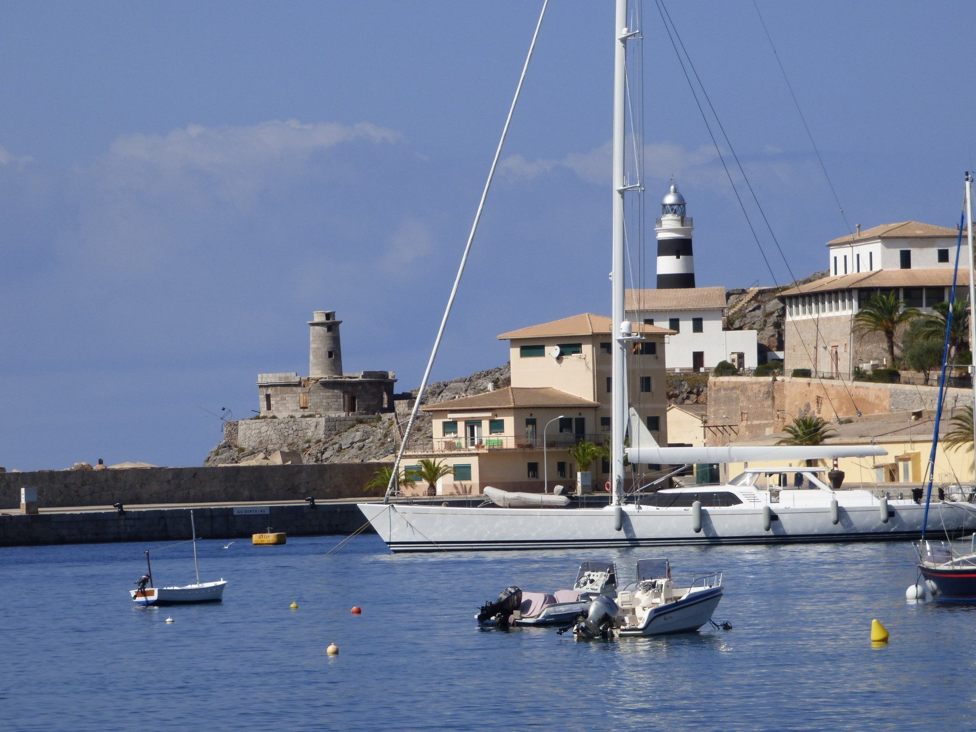 A sailboat is docked in a harbor with a lighthouse in the background