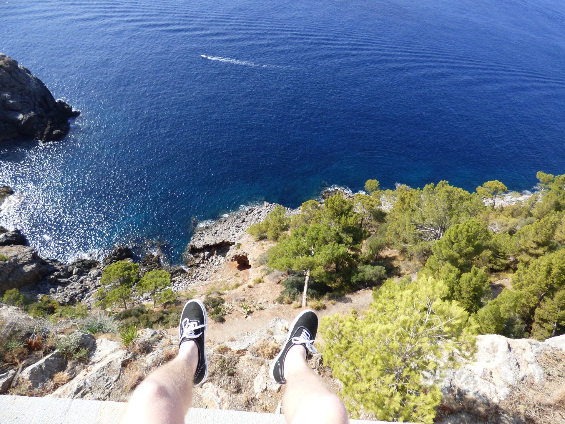 A person 's feet are hanging over a cliff overlooking the ocean