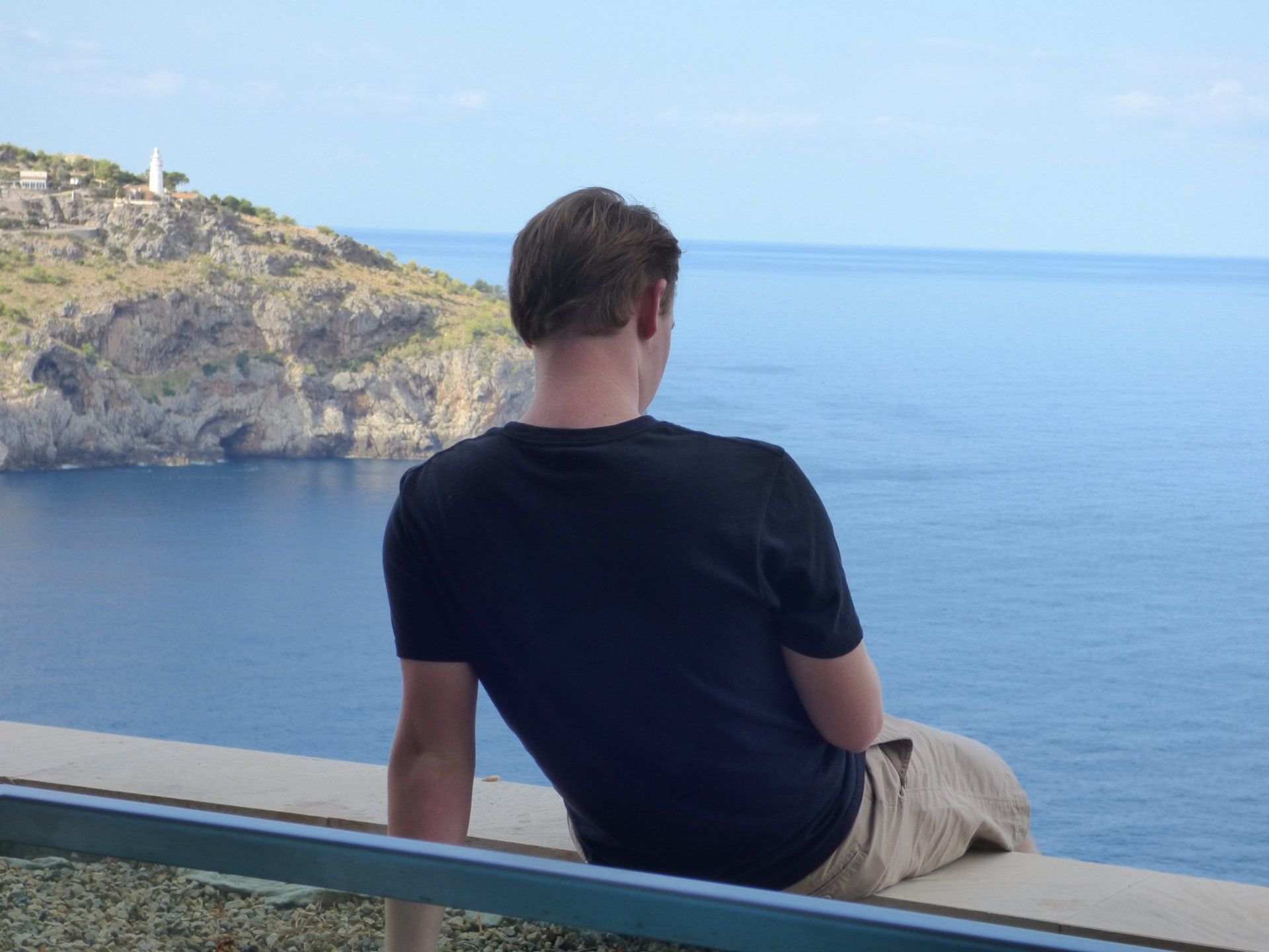 A man is sitting on a bench overlooking the ocean
