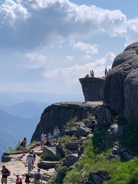 A group of people are standing on top of a rocky cliff.