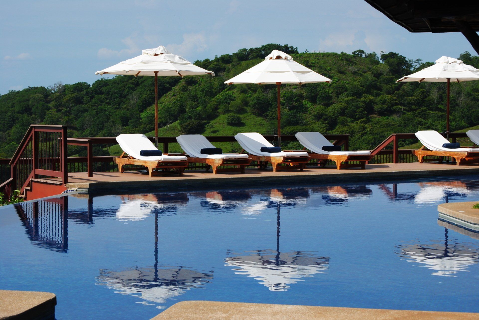 A swimming pool with chairs and umbrellas around it