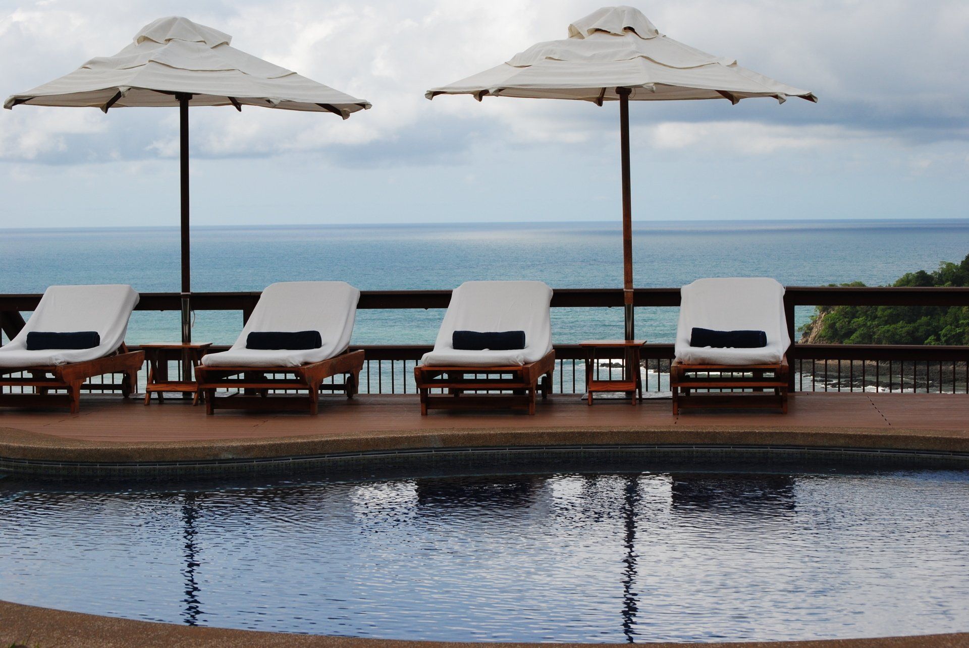A swimming pool with chairs and umbrellas overlooking the ocean