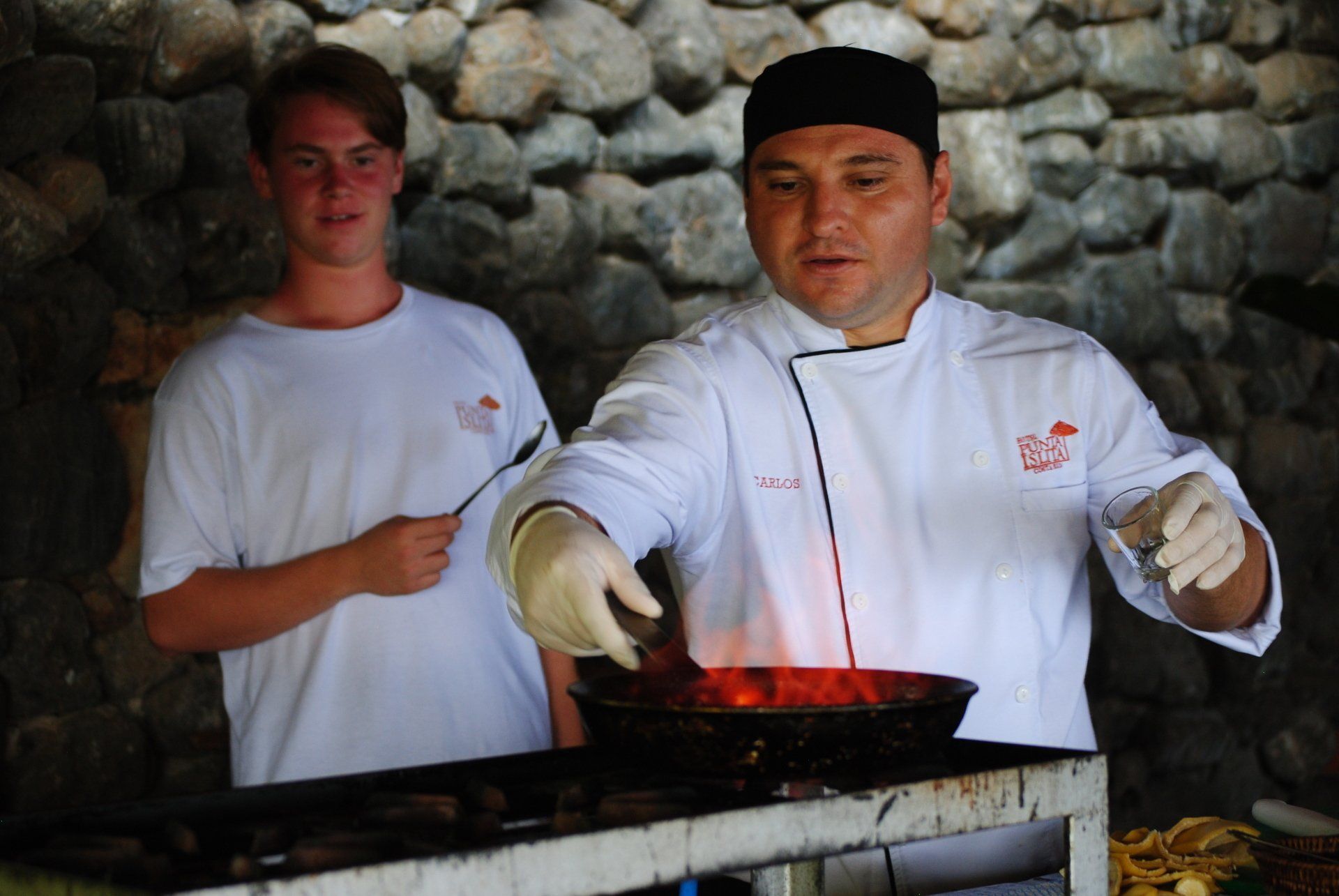 A man in a chef 's uniform is cooking in a frying pan