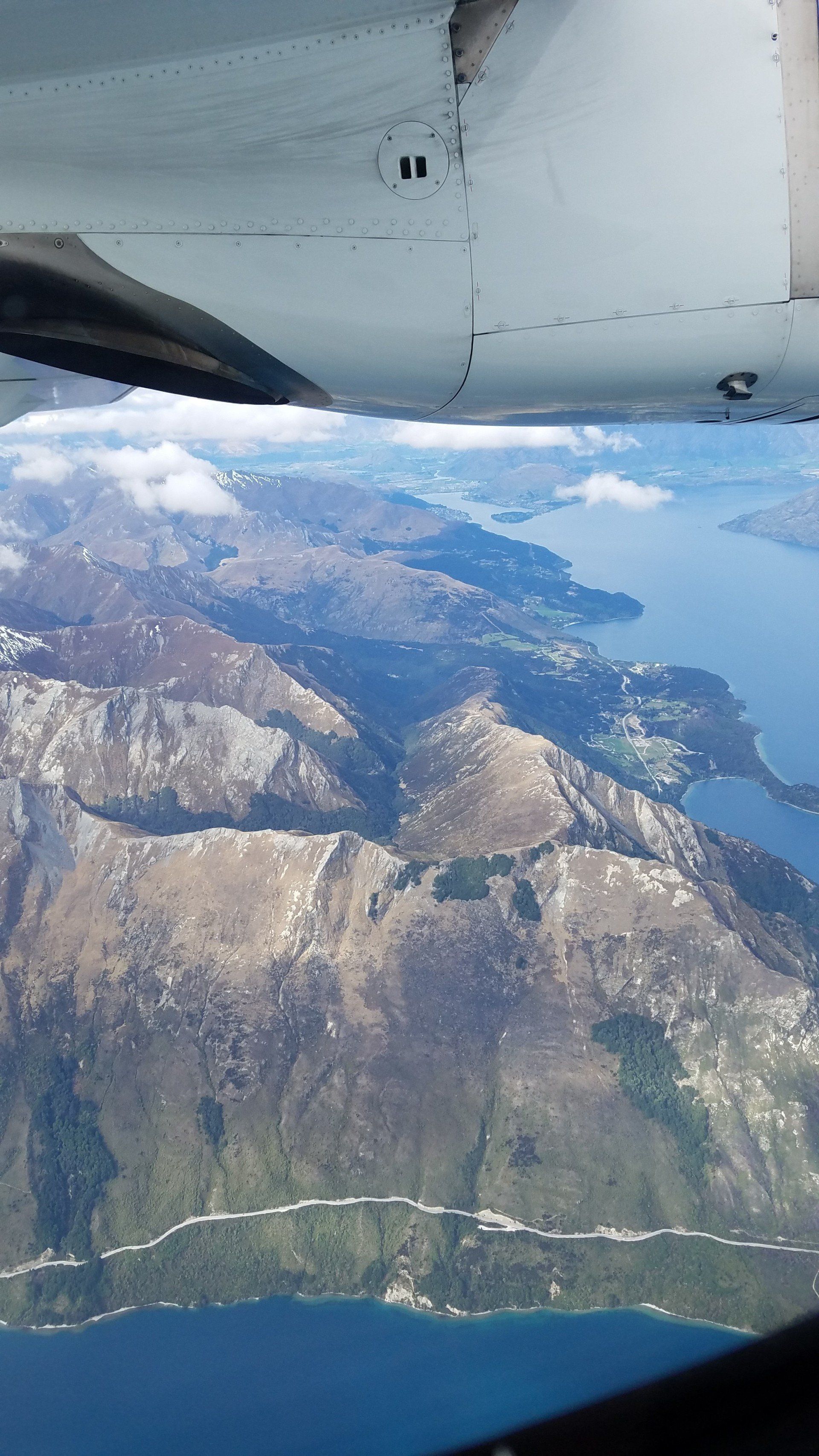 An aerial view of mountains and a lake from an airplane window.