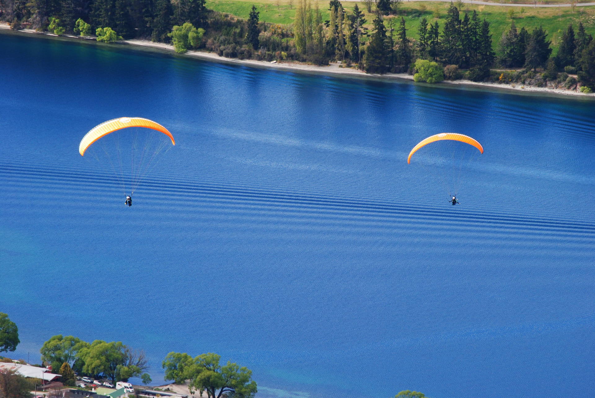 Two paragliders are flying over a large body of water