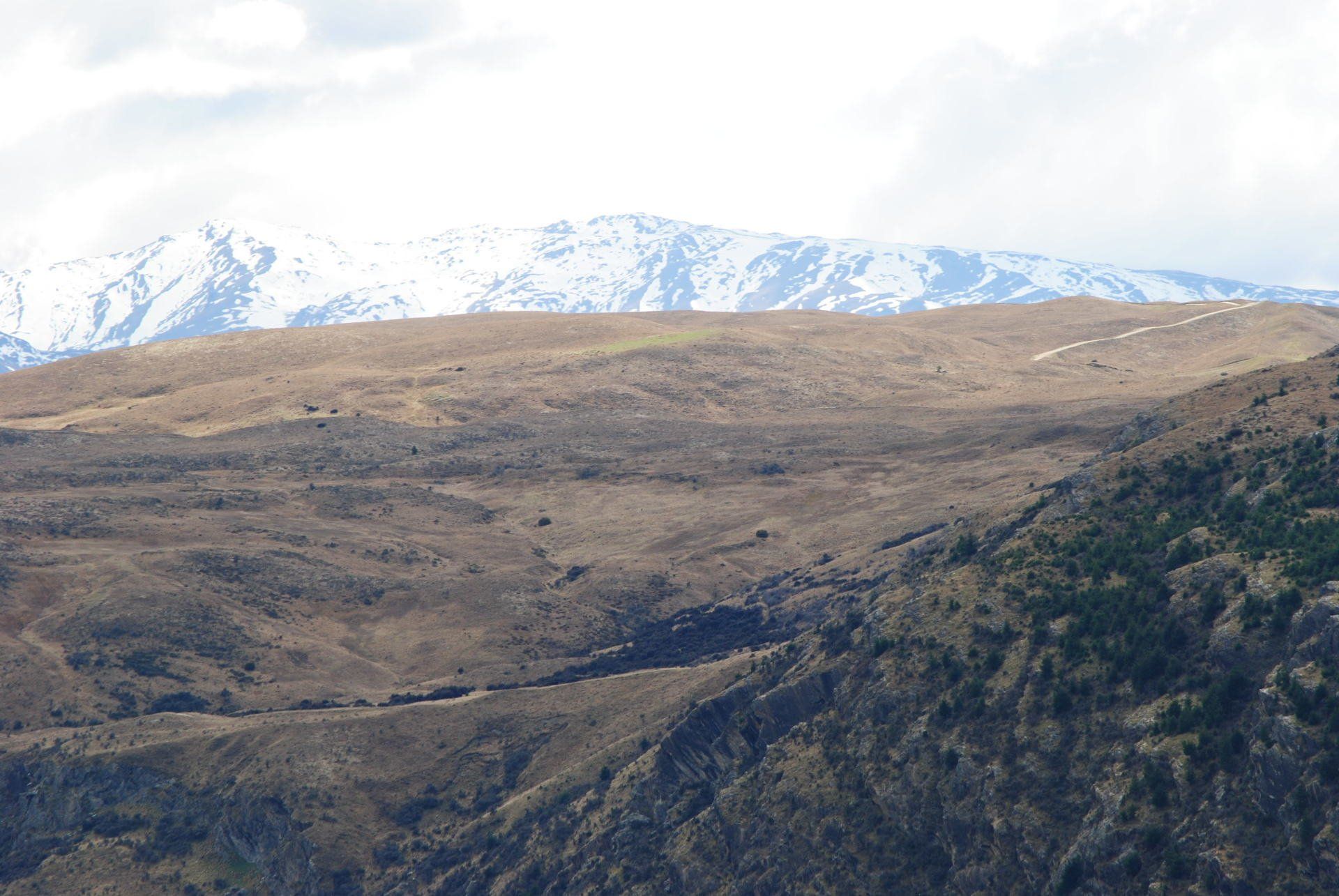 A mountain range with snow on the peaks and a road going through it