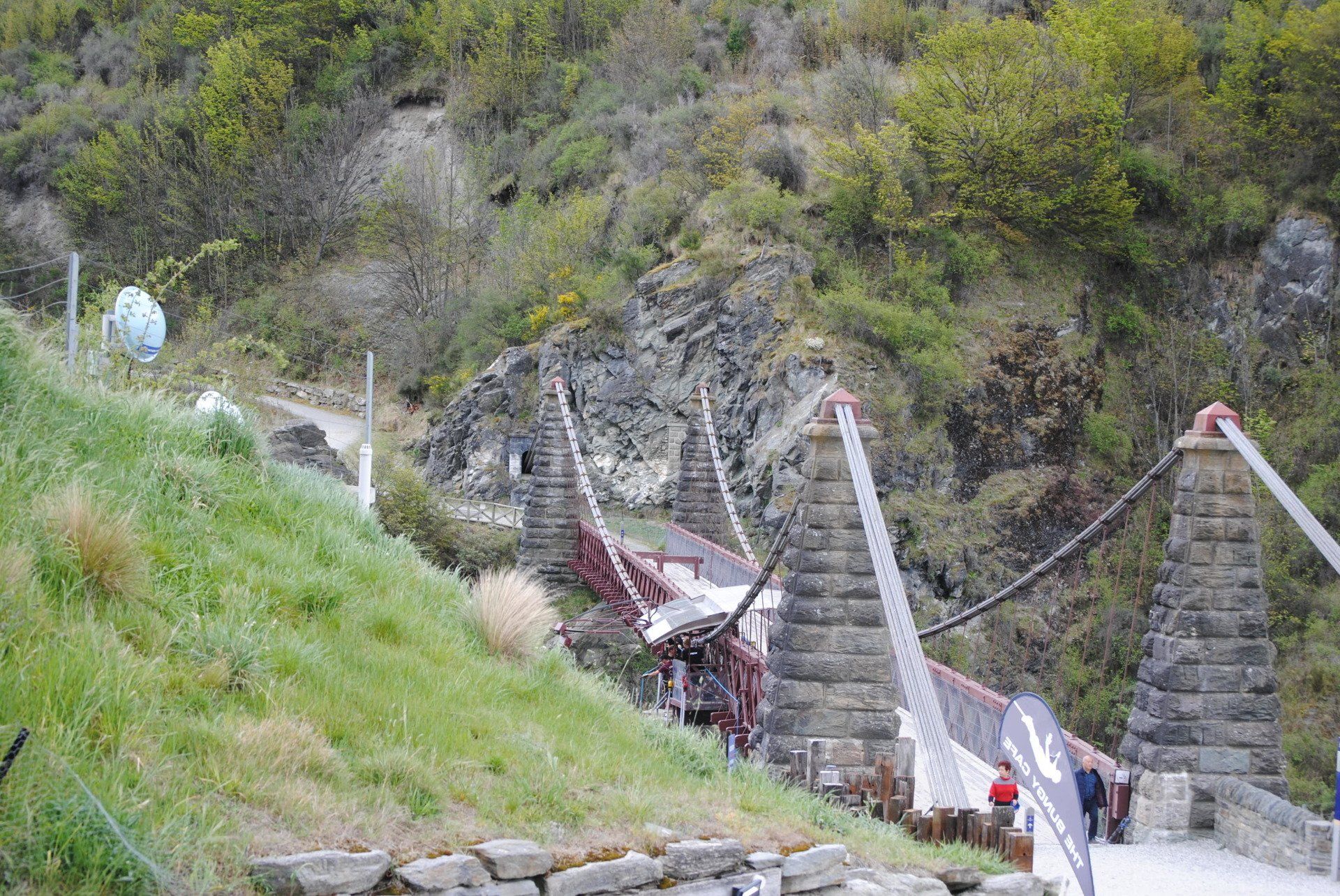 A bridge over a river in the mountains with people walking on it.
