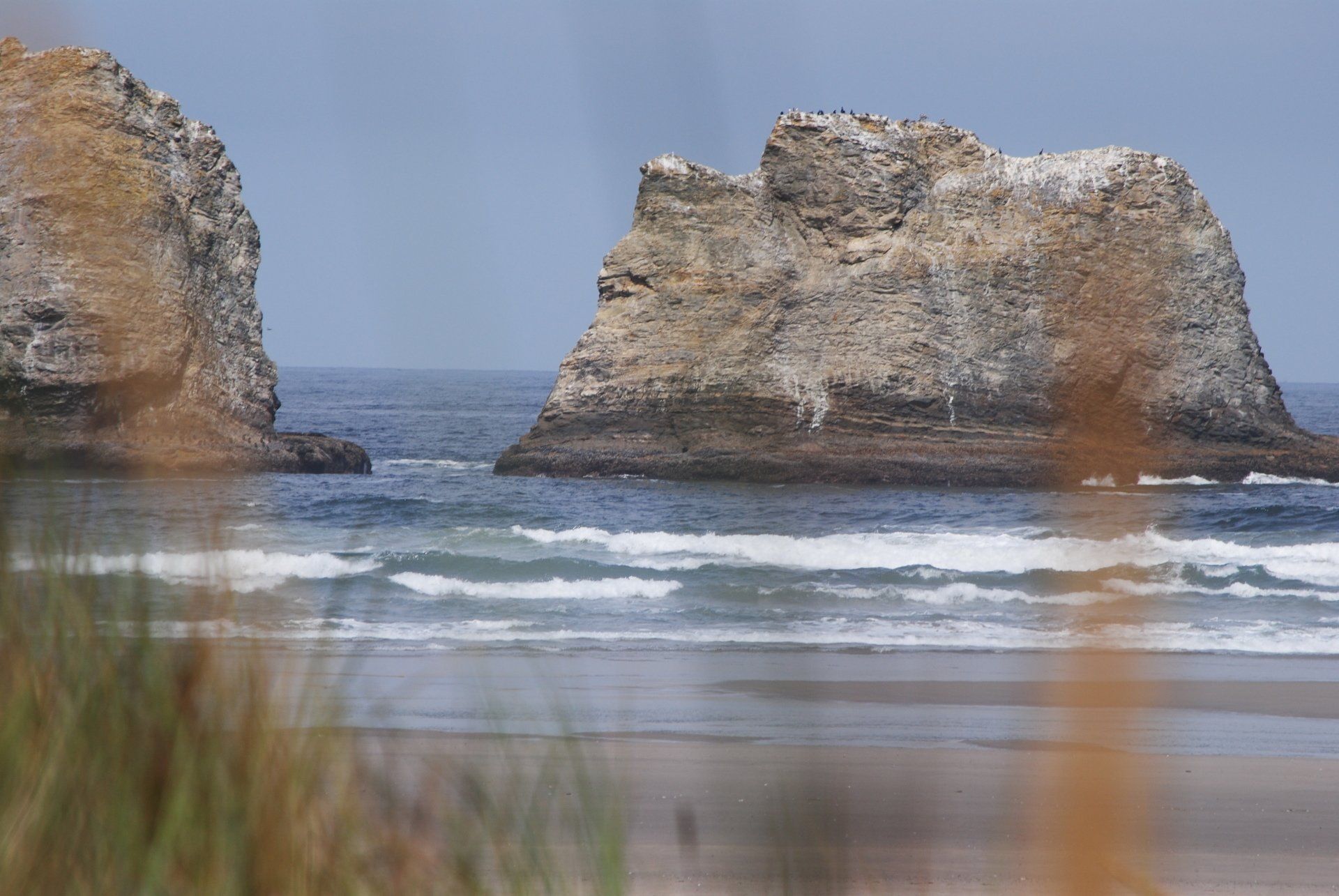 A couple of rocks sitting on top of a beach next to the ocean.