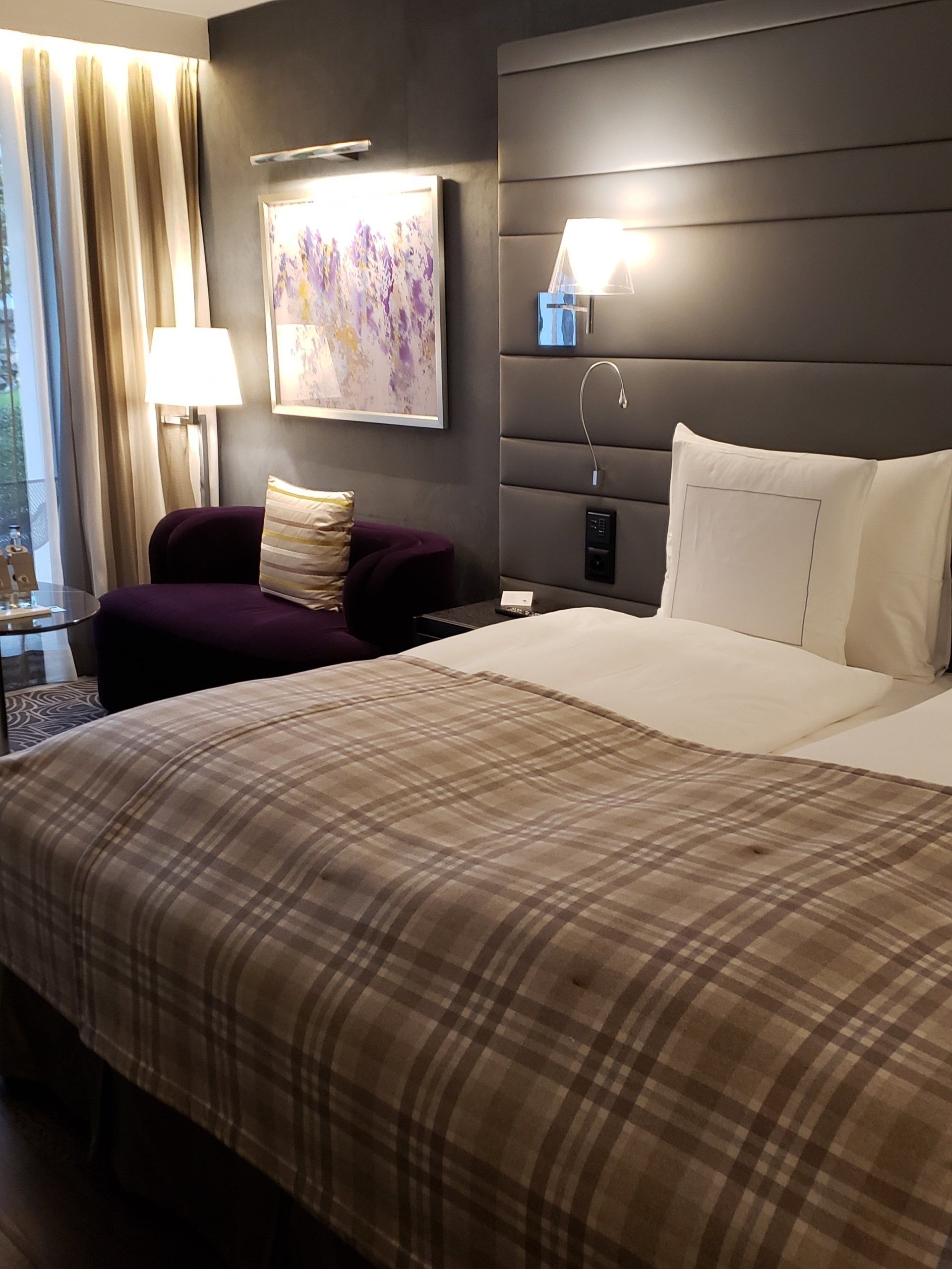 A hotel room with a king size bed and a purple chair