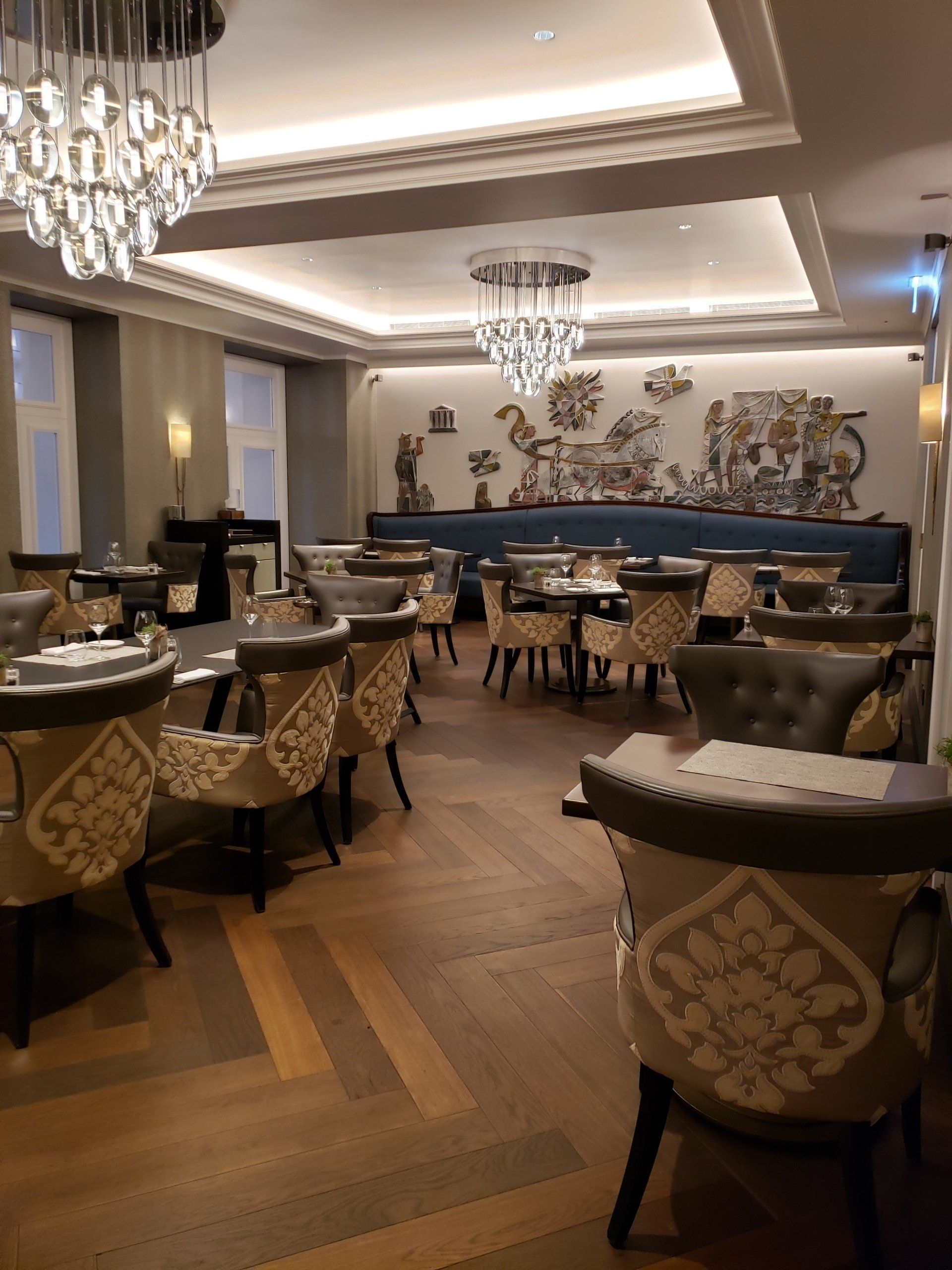 A large dining room with tables and chairs and a chandelier.
