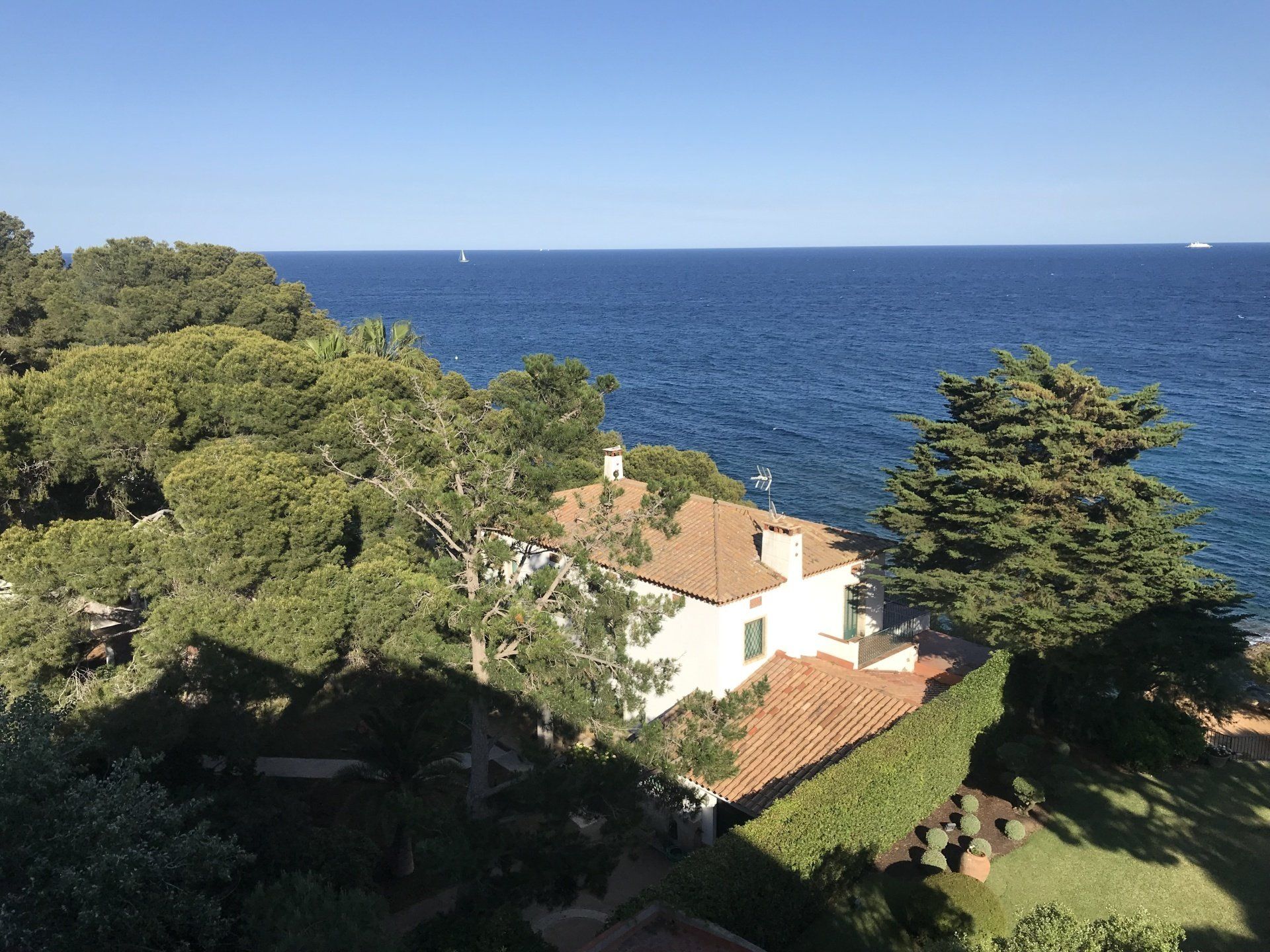 There is a house on the shore of the ocean surrounded by trees.