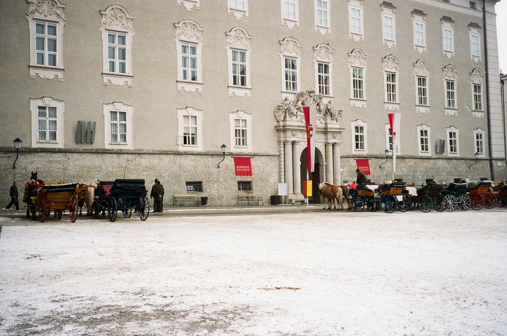 Horse drawn carriages are parked in front of a large building