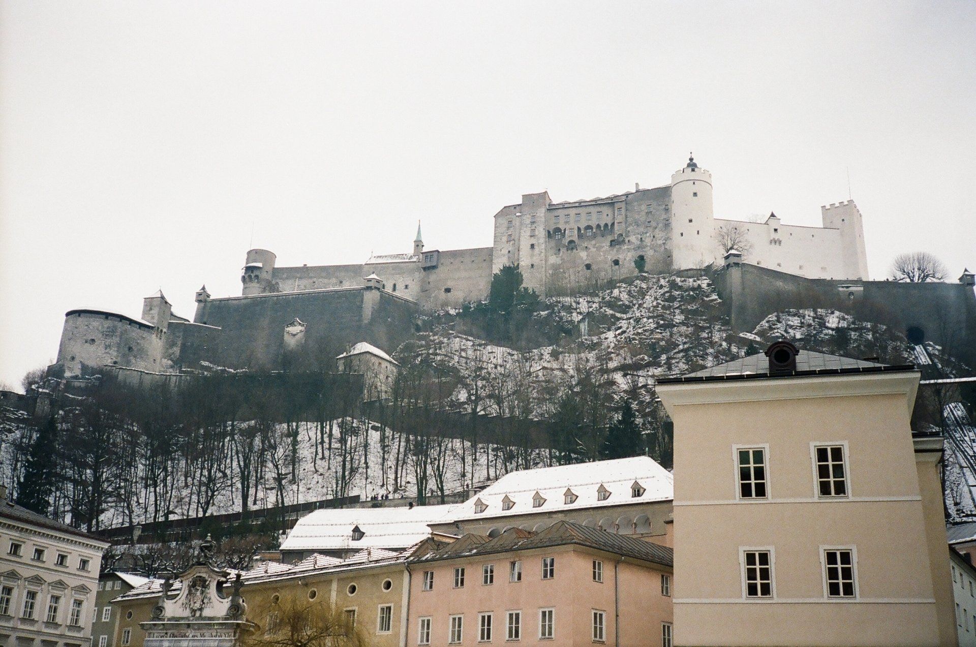 A castle sits on top of a snow covered hill