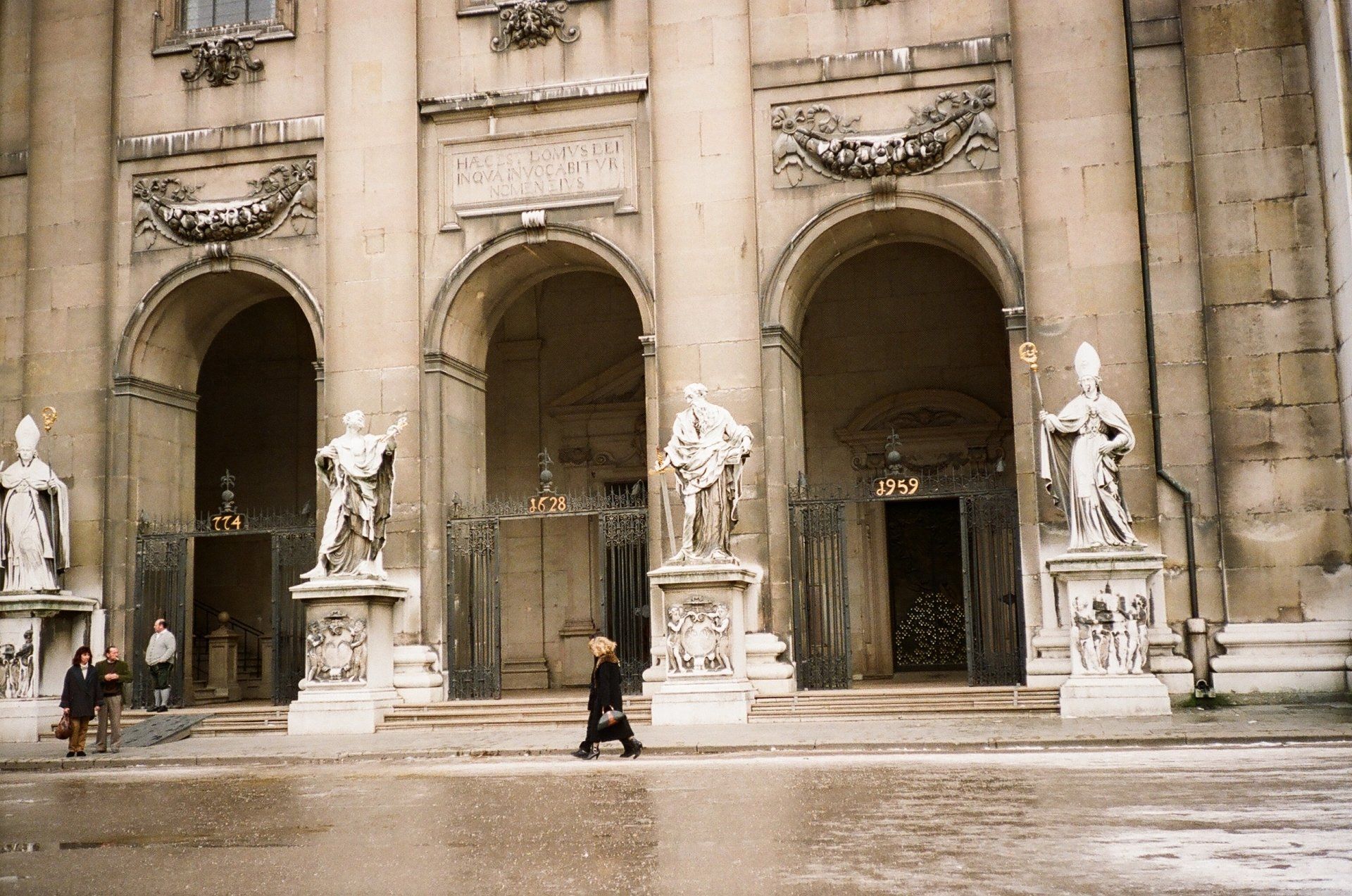 A man walking in front of a building with statues on it