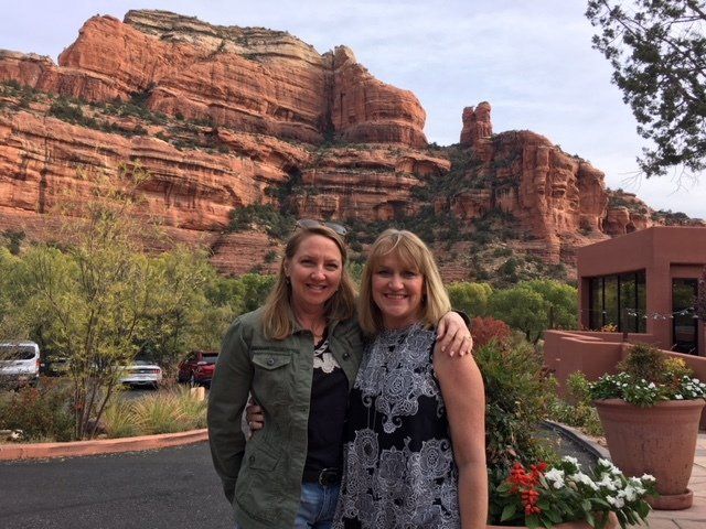 Two women are posing for a picture in front of a mountain.