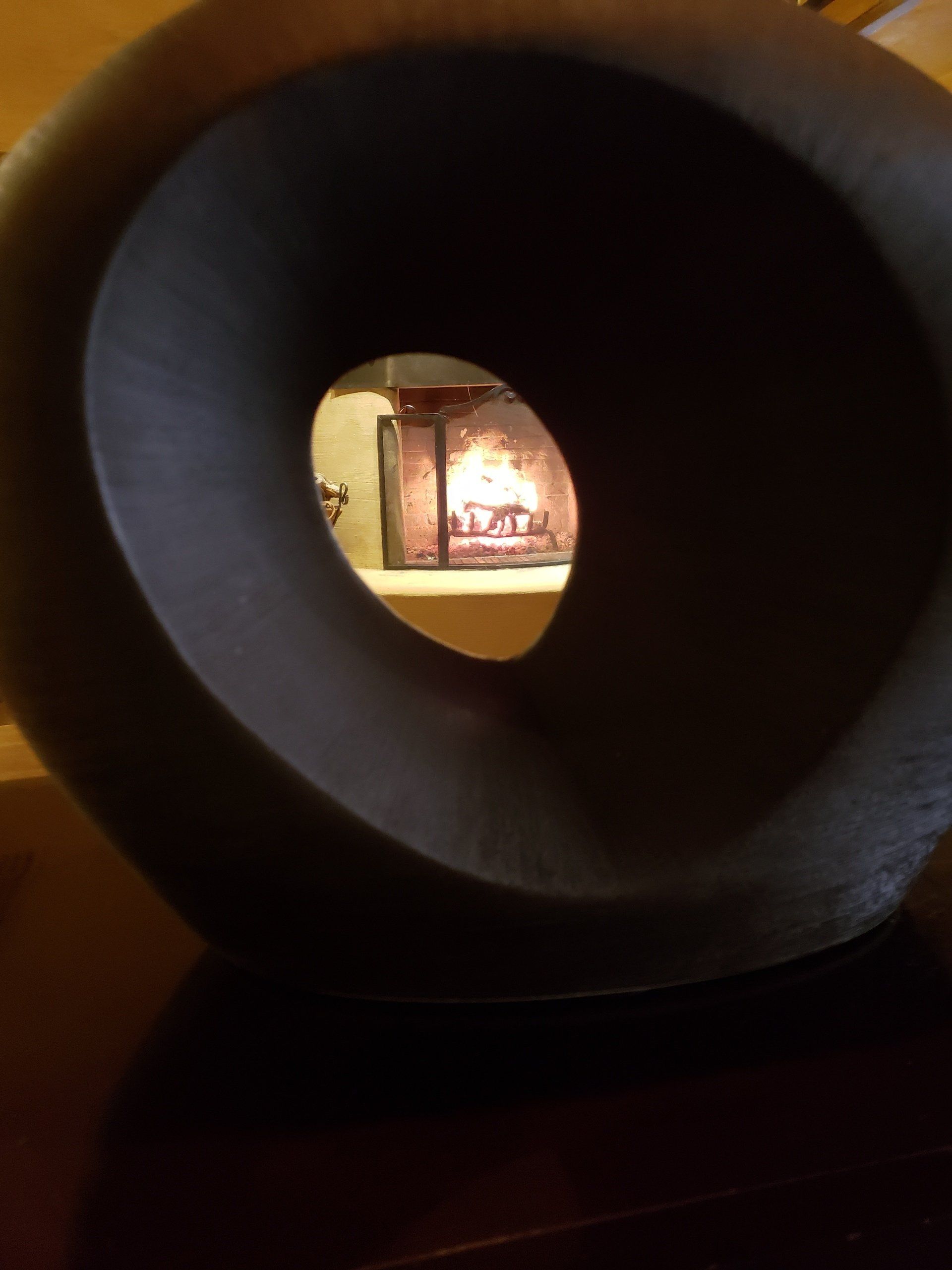 A circular object with a hole in the middle is sitting on a table in front of a fireplace.