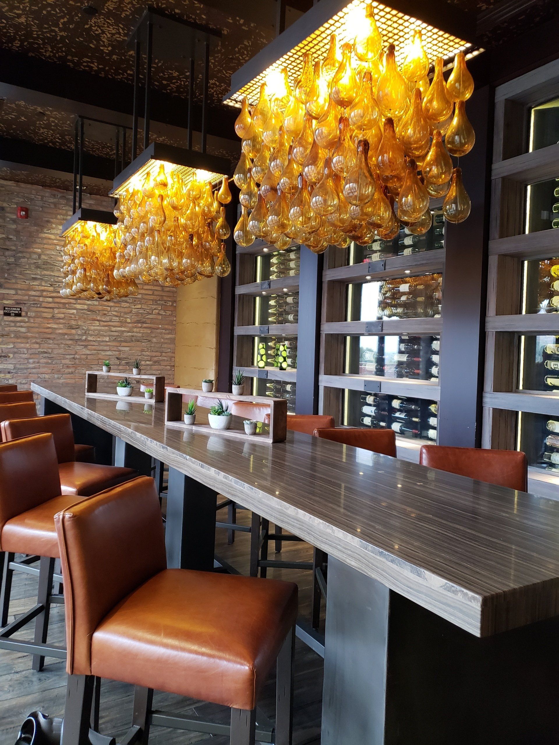 A long bar with a lot of glasses hanging from the ceiling