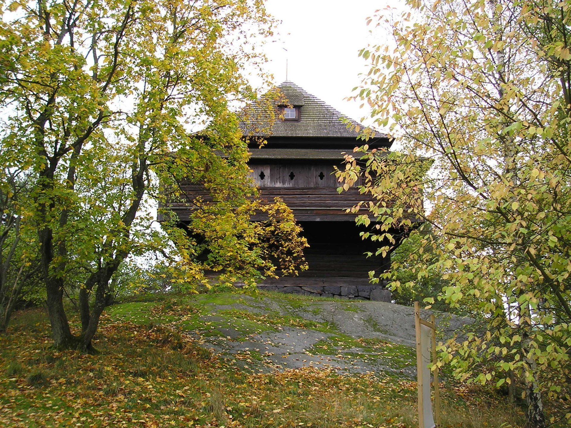 A large wooden building is surrounded by trees and grass