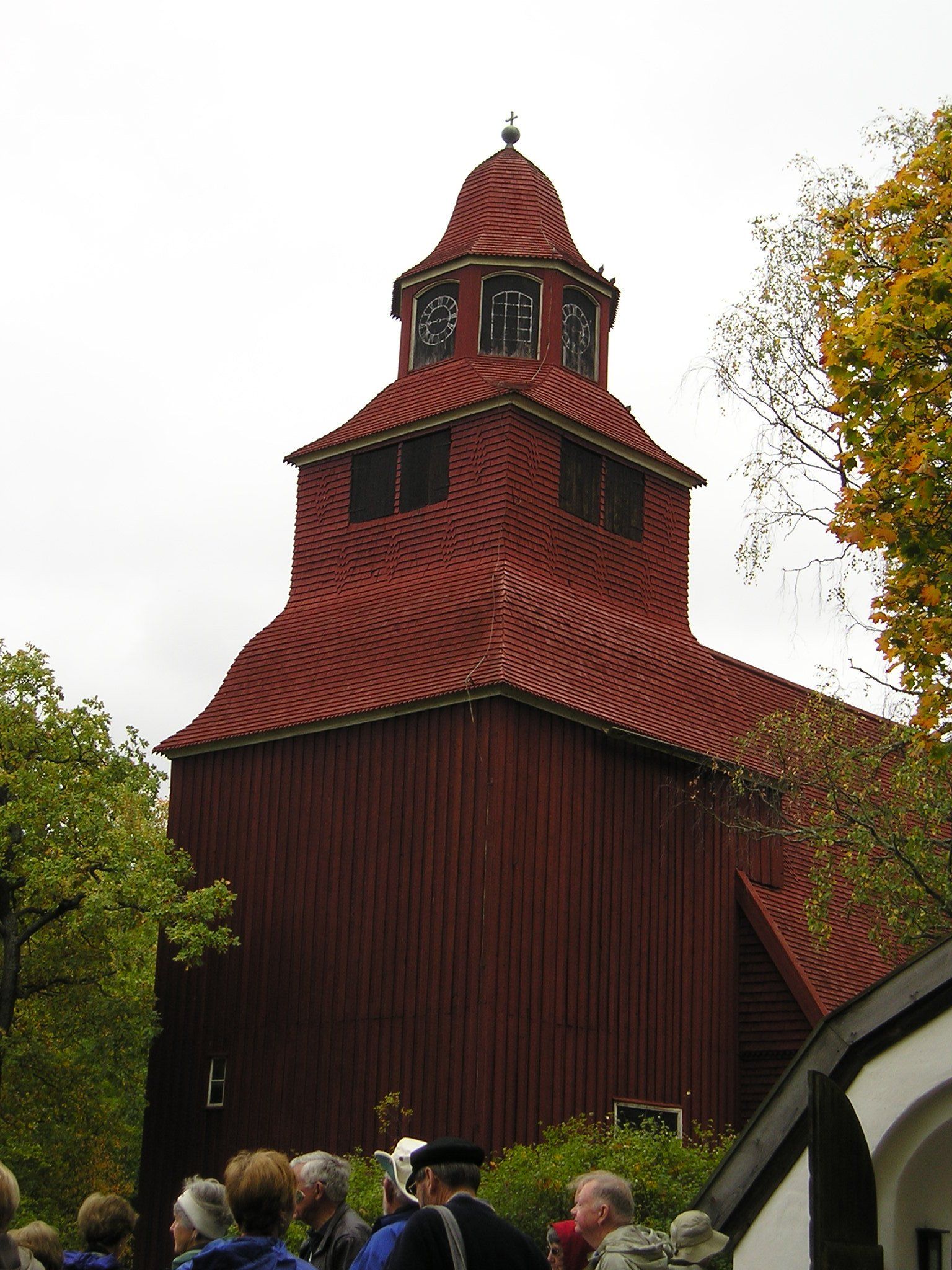 A group of people are standing in front of a large red building with a clock tower